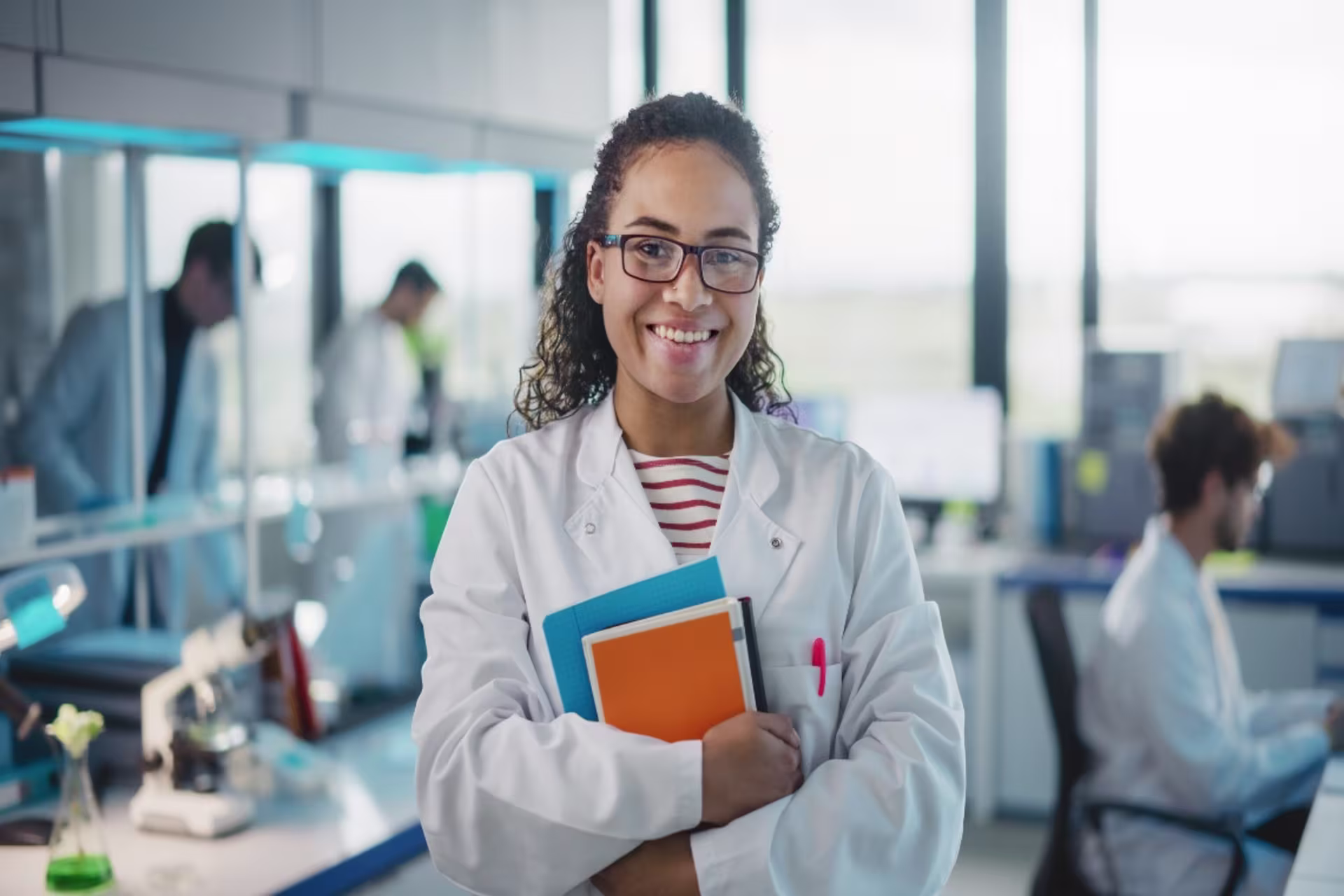 Chemistry student in lab setting smiling and holding textbooks