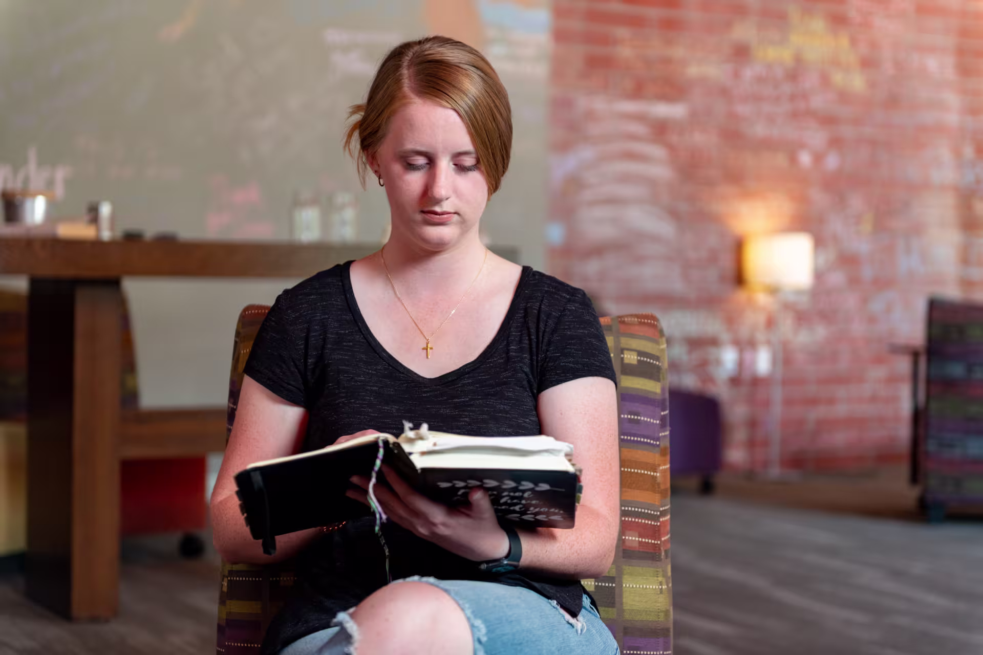 Female MA in Christian Leadership student reading Bible at home