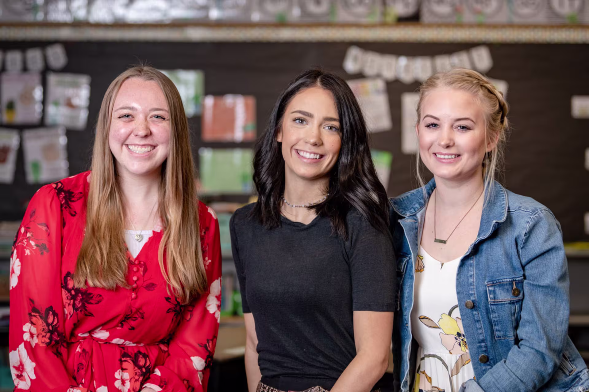 Group of female elementary education teachers in classroom smiling at camera