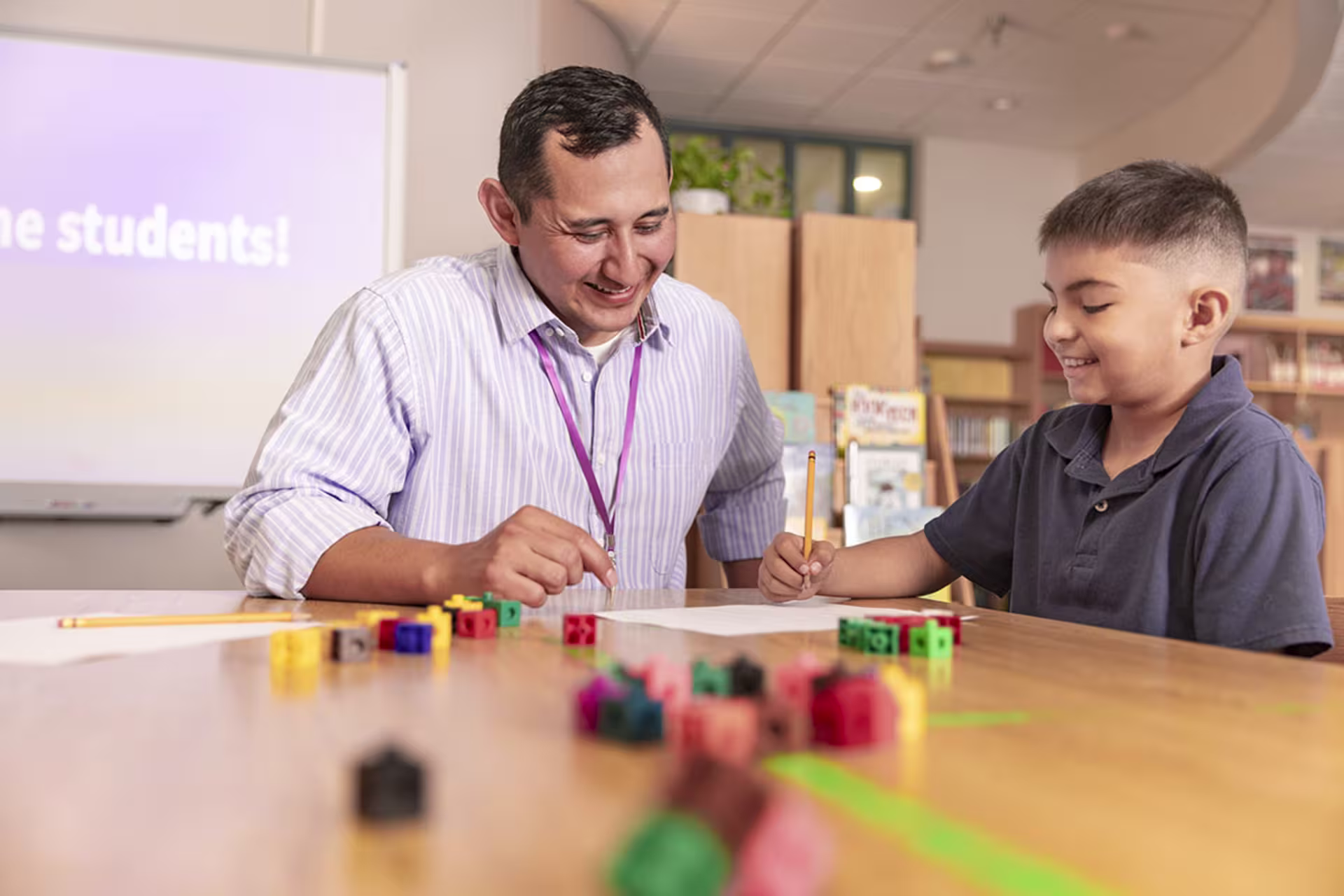 Male elementary education teacher playing a game with young male student