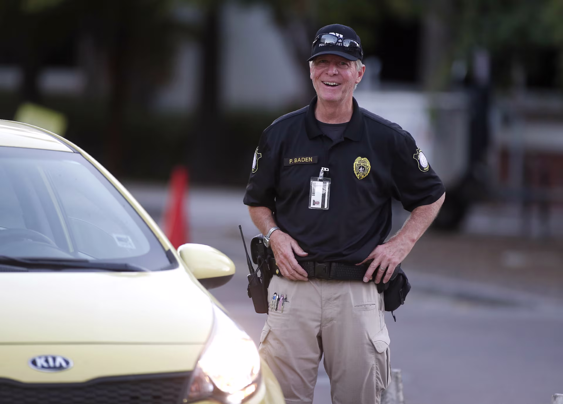 Security man standing and smiling next to a car