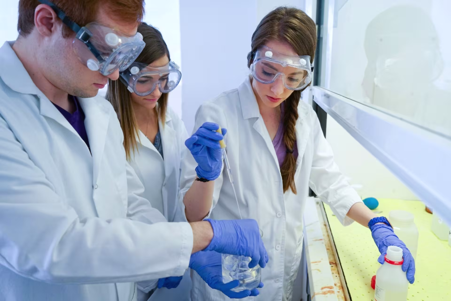 Three chemistry students in lab working on experiments