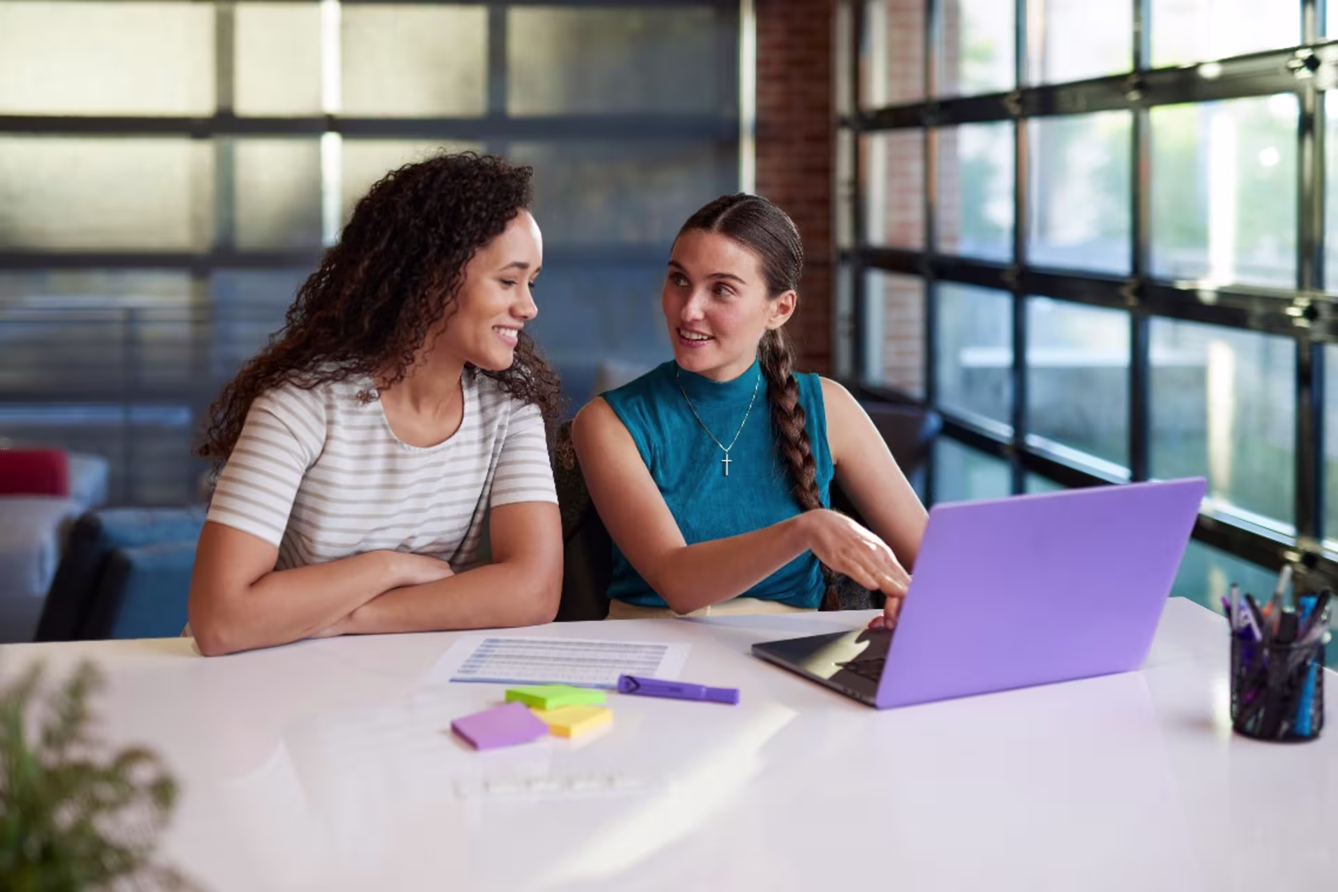 Two marketing students working on coursework with laptops and notes