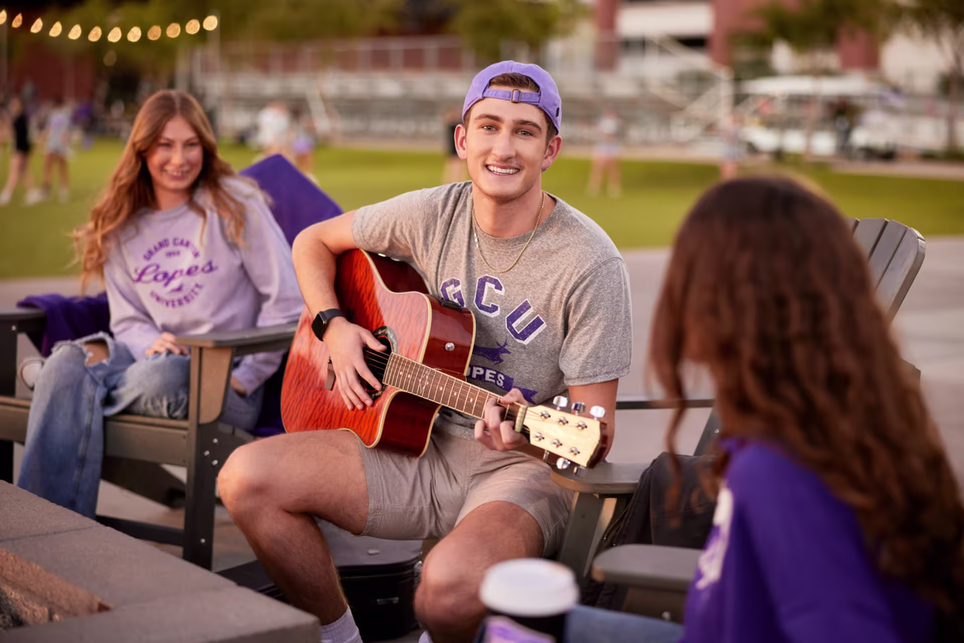 GCU student playing guitar outdoors with friends, showcasing the university's music community.