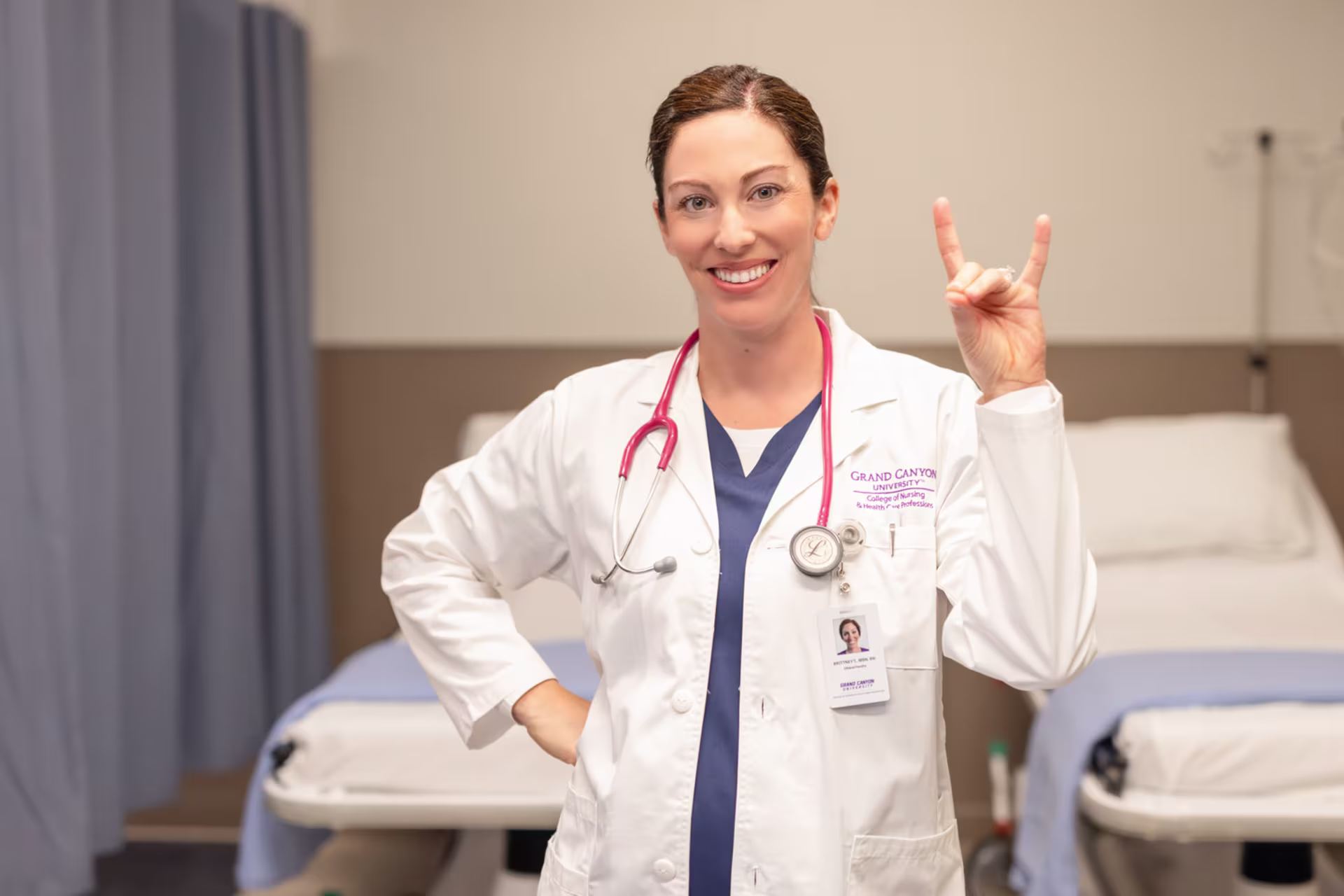 dnp nurse in a hospital environment giving lopes up hand symbol