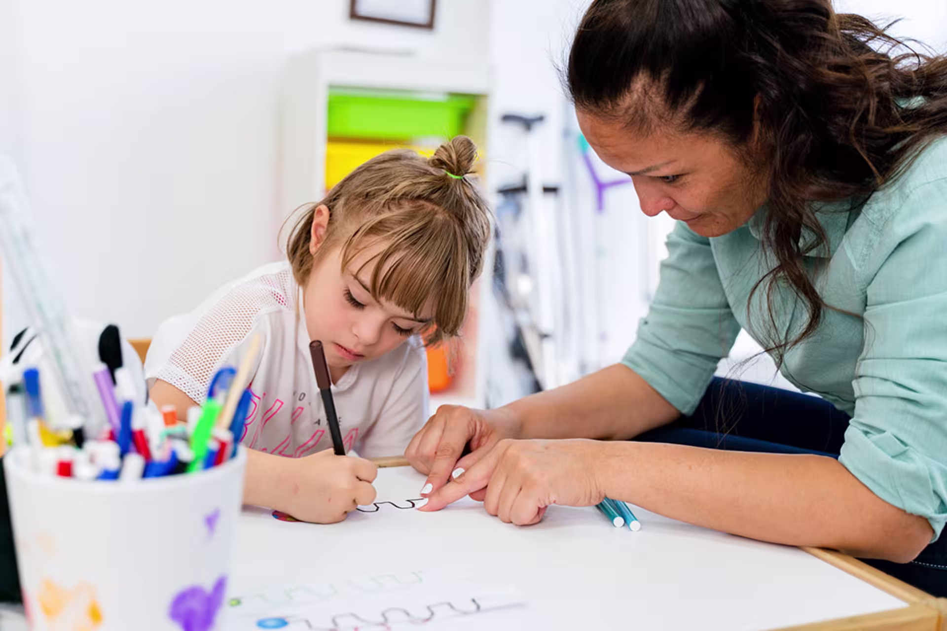 Female ECSE teacher working with young female student on drawings