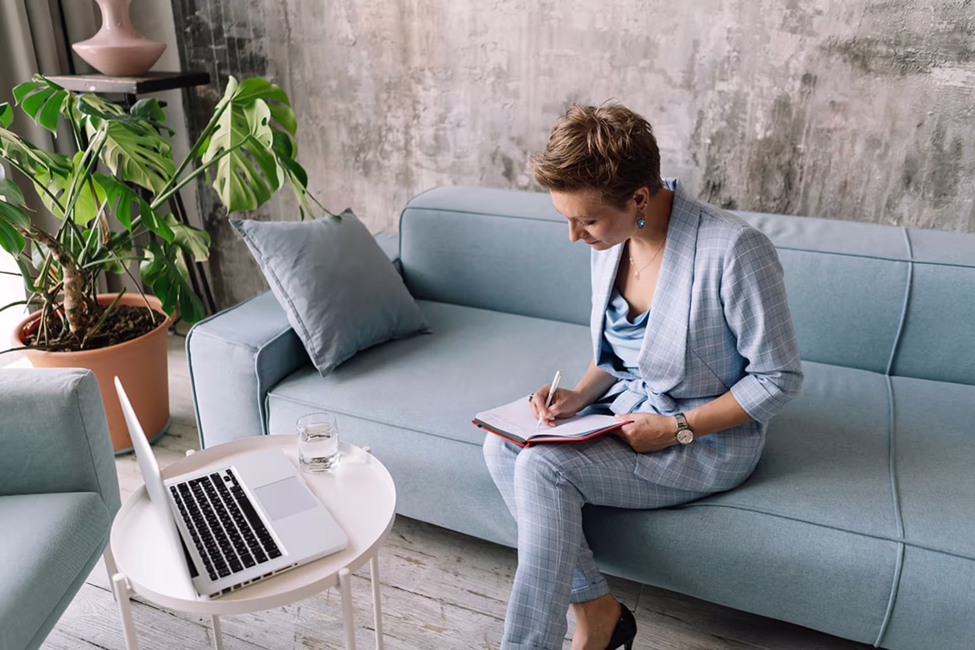 Female health psychiatrist sitting on sofa conducting telemedicine video call on laptop