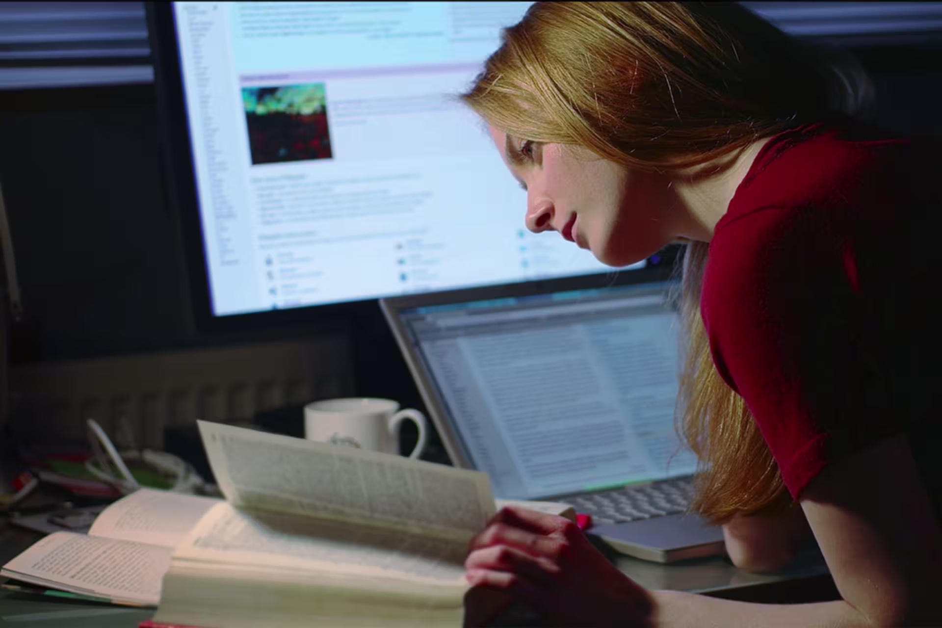 Female MA English with an emphasis in Education student studying a book and also using a computer at home