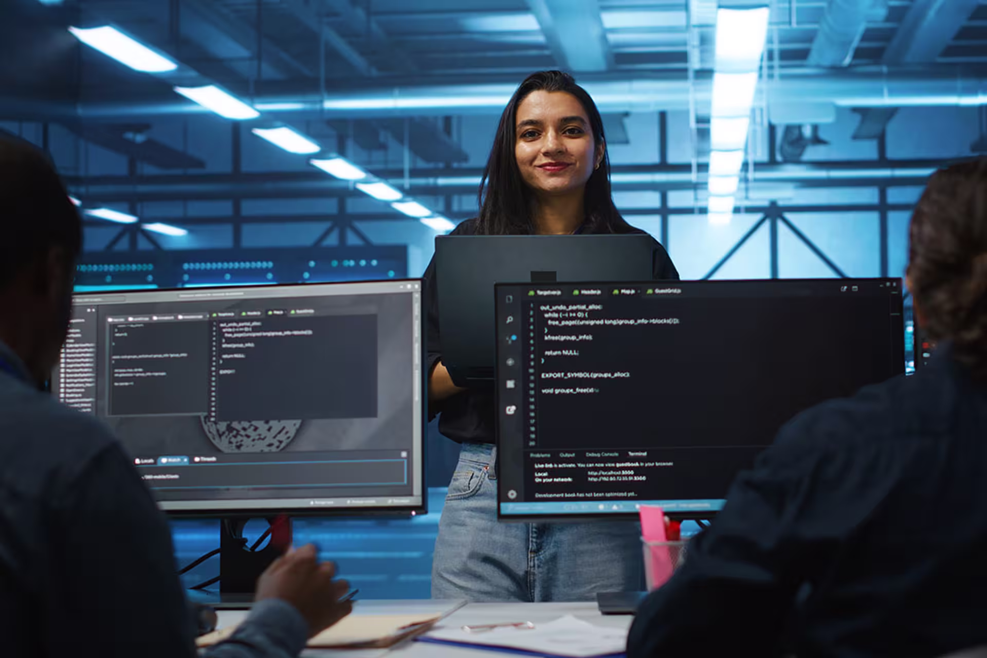 Focused shot of female database engineer smiling at camera and facing colleagues for support 
