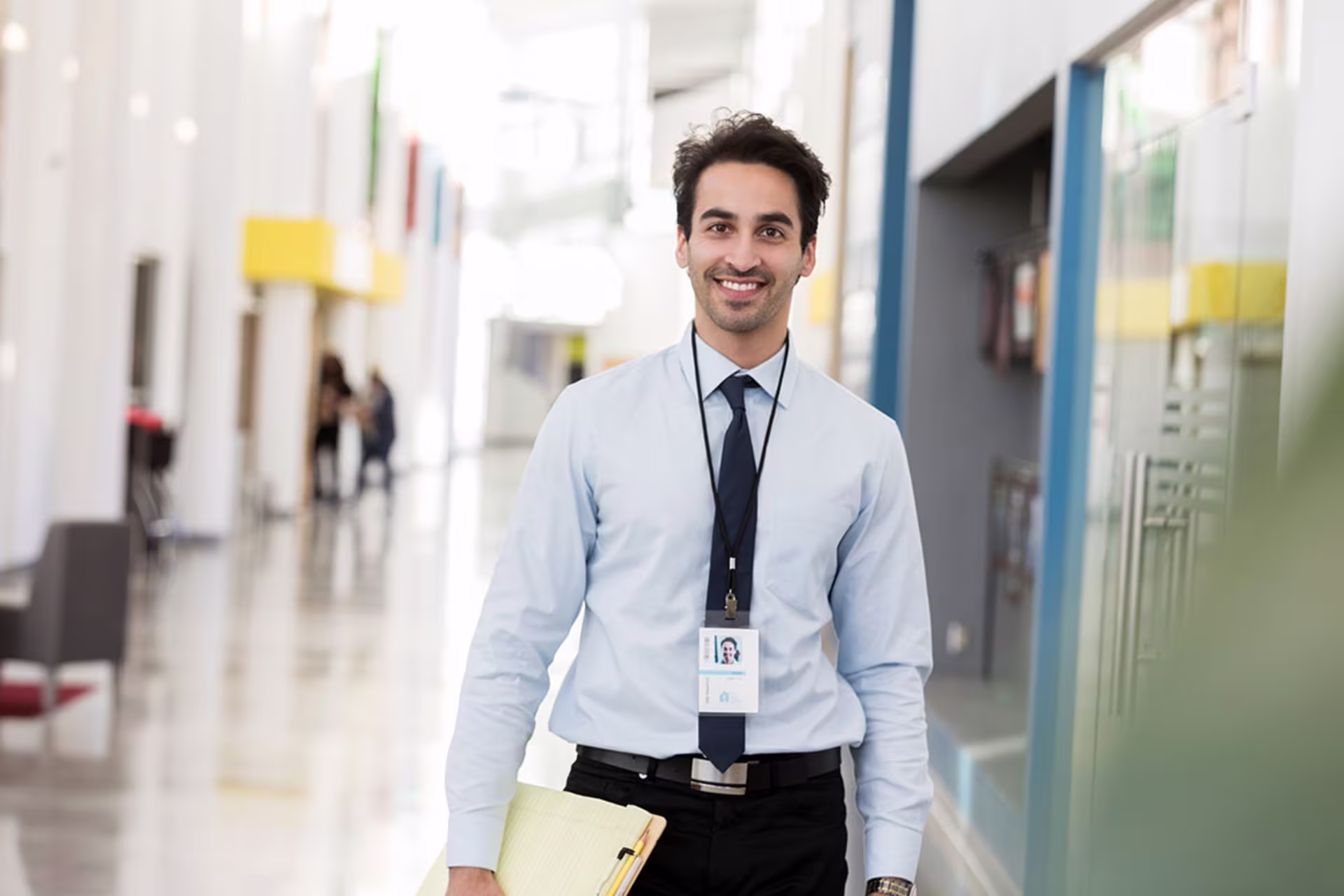 Male school administrator walking down school hallway holding file folders