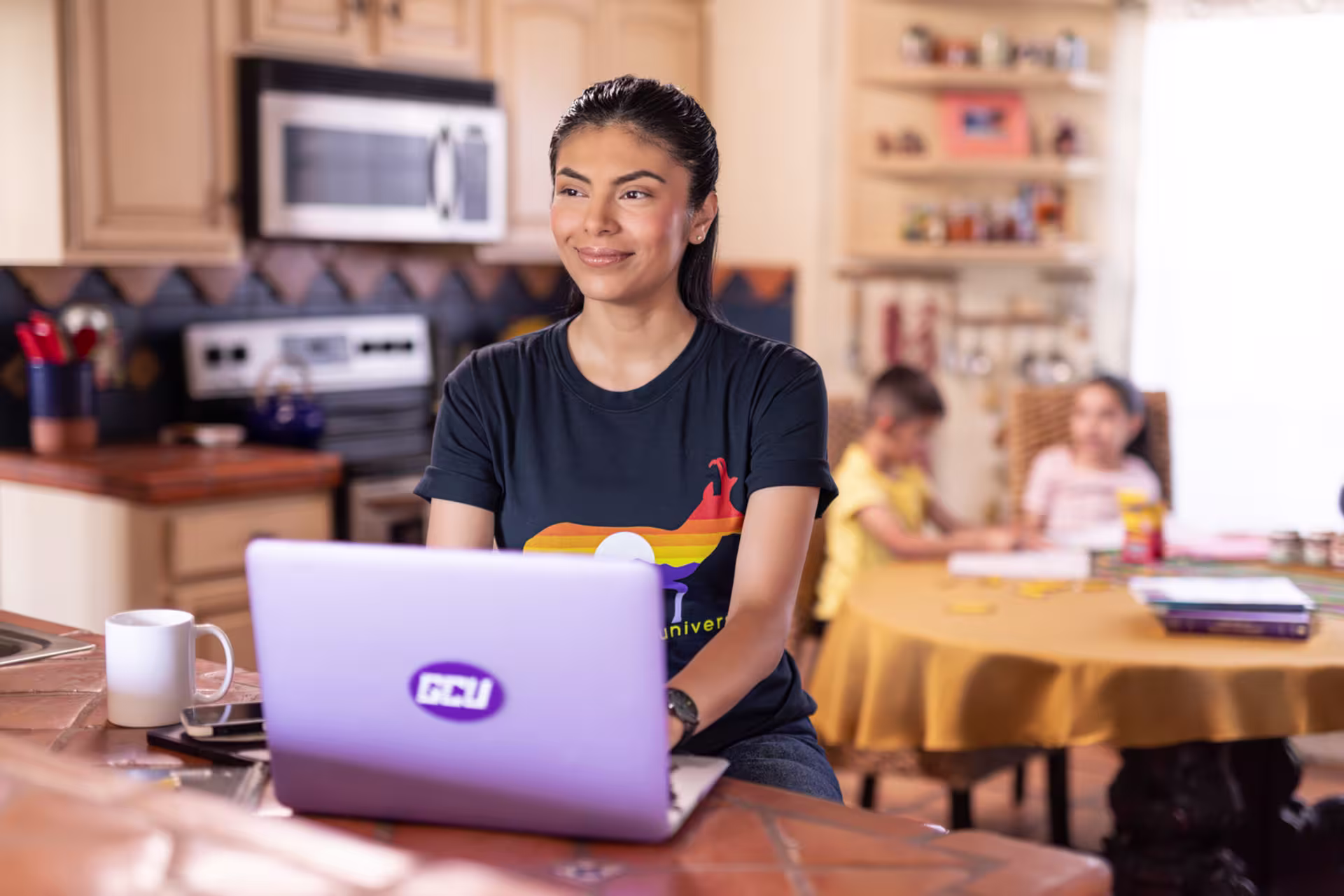 A nursing student taking the Post-MSN Nursing Certificate program online, studying at home with a laptop while children play in the background.