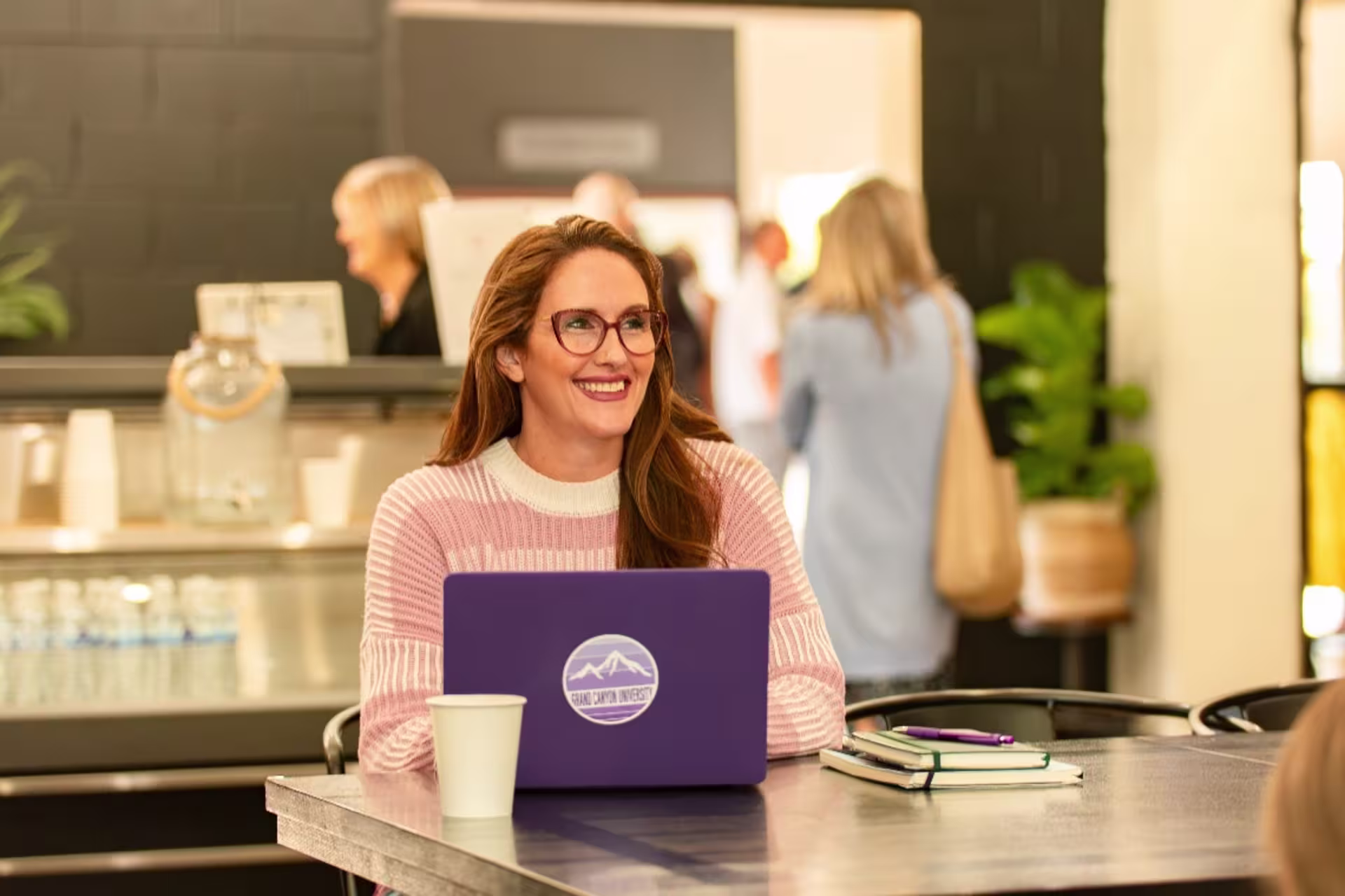 Online counseling student working on a laptop in a coffee shop