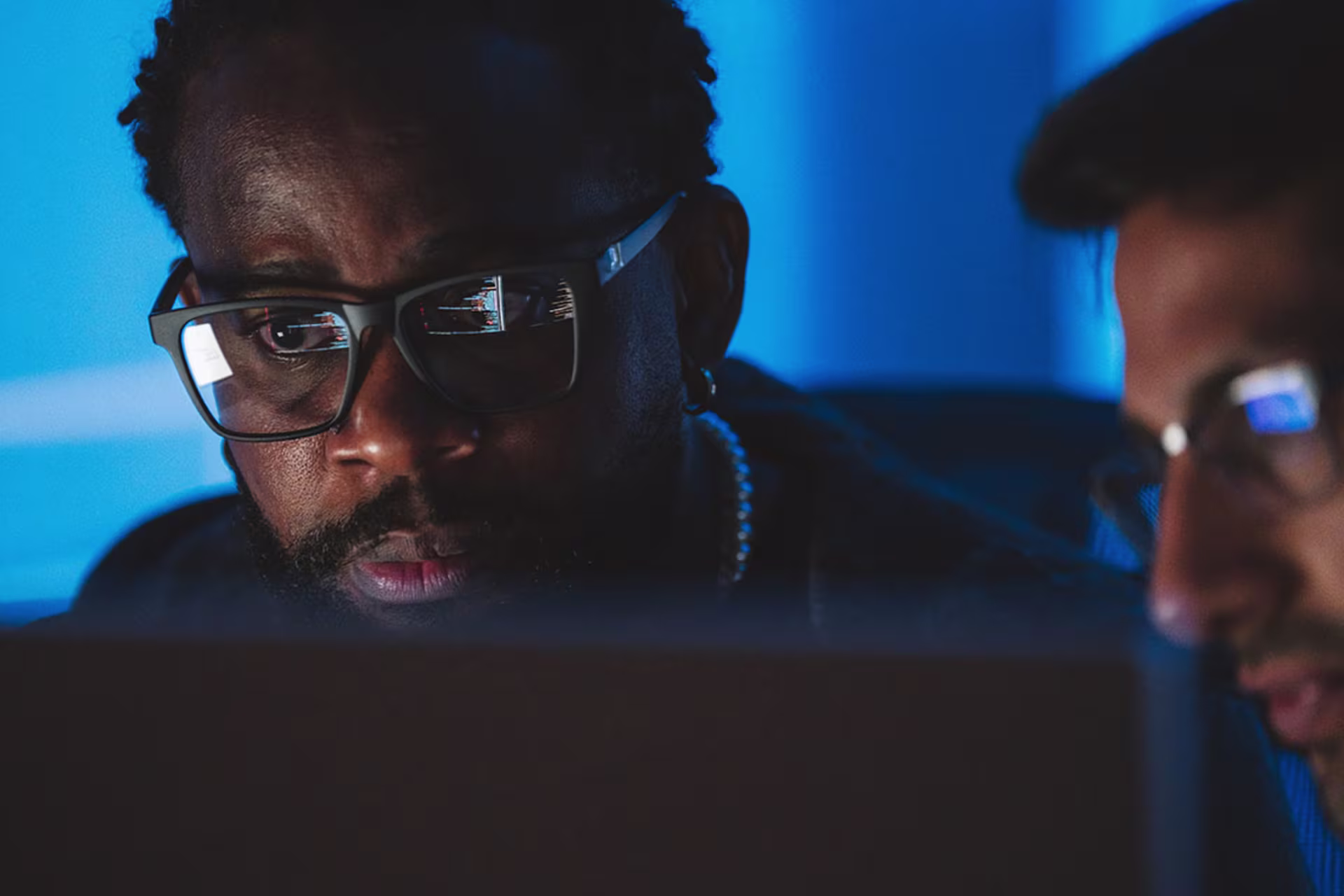 Two male database administrators looking through strings of code on computer