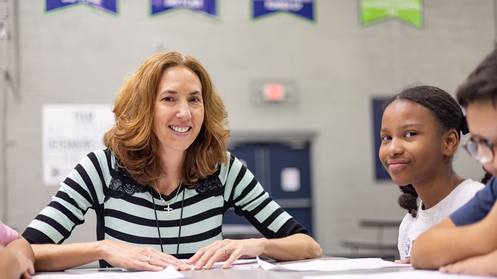 Female teacher working with young students at table