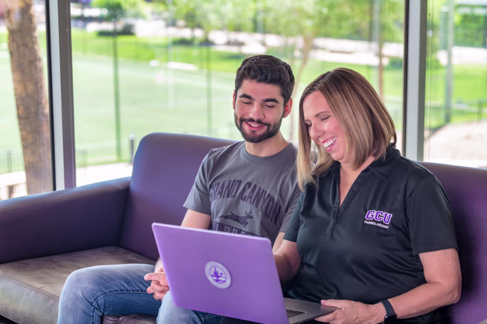 Female university counselor helping male student with estimating costs online