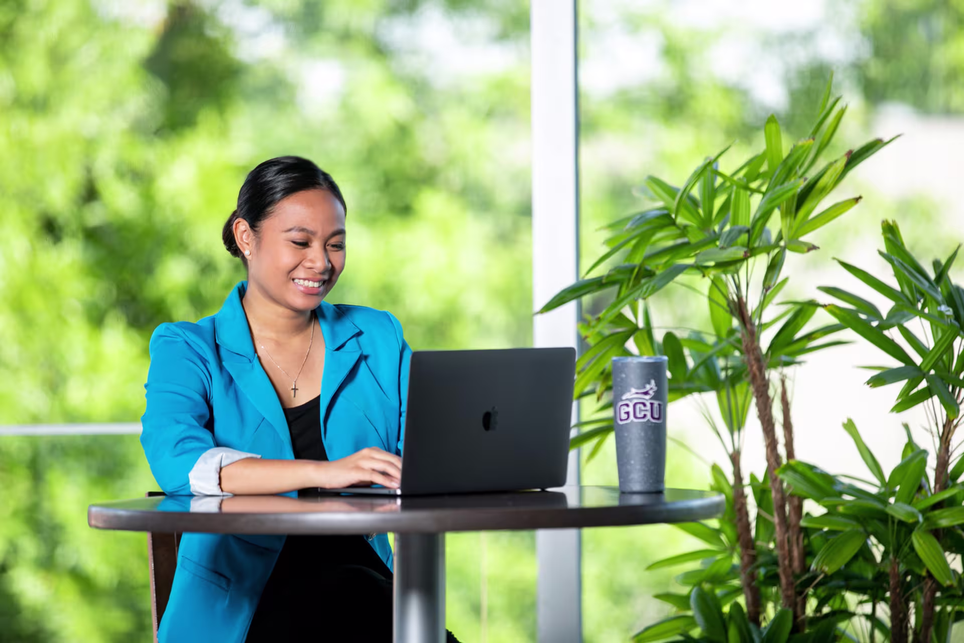 Headshot of woman in blue suit jacket working on laptop in office