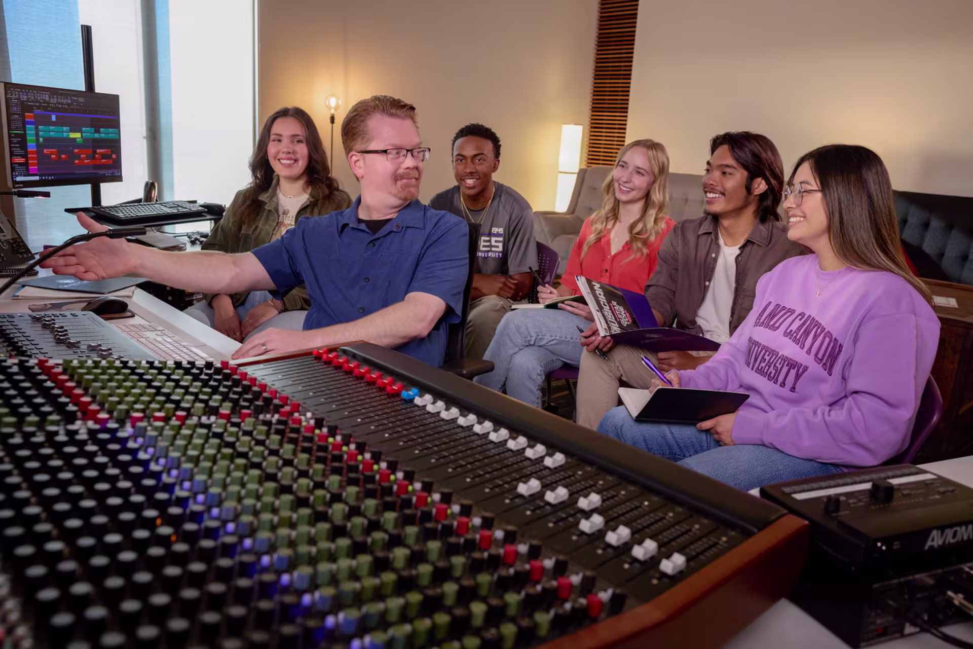 Male teacher and group of worship arts majors in studio producing music