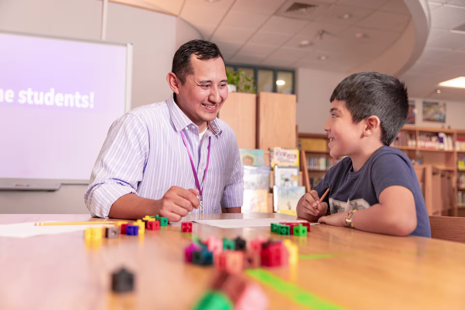Male teacher helping young male student with homework in library