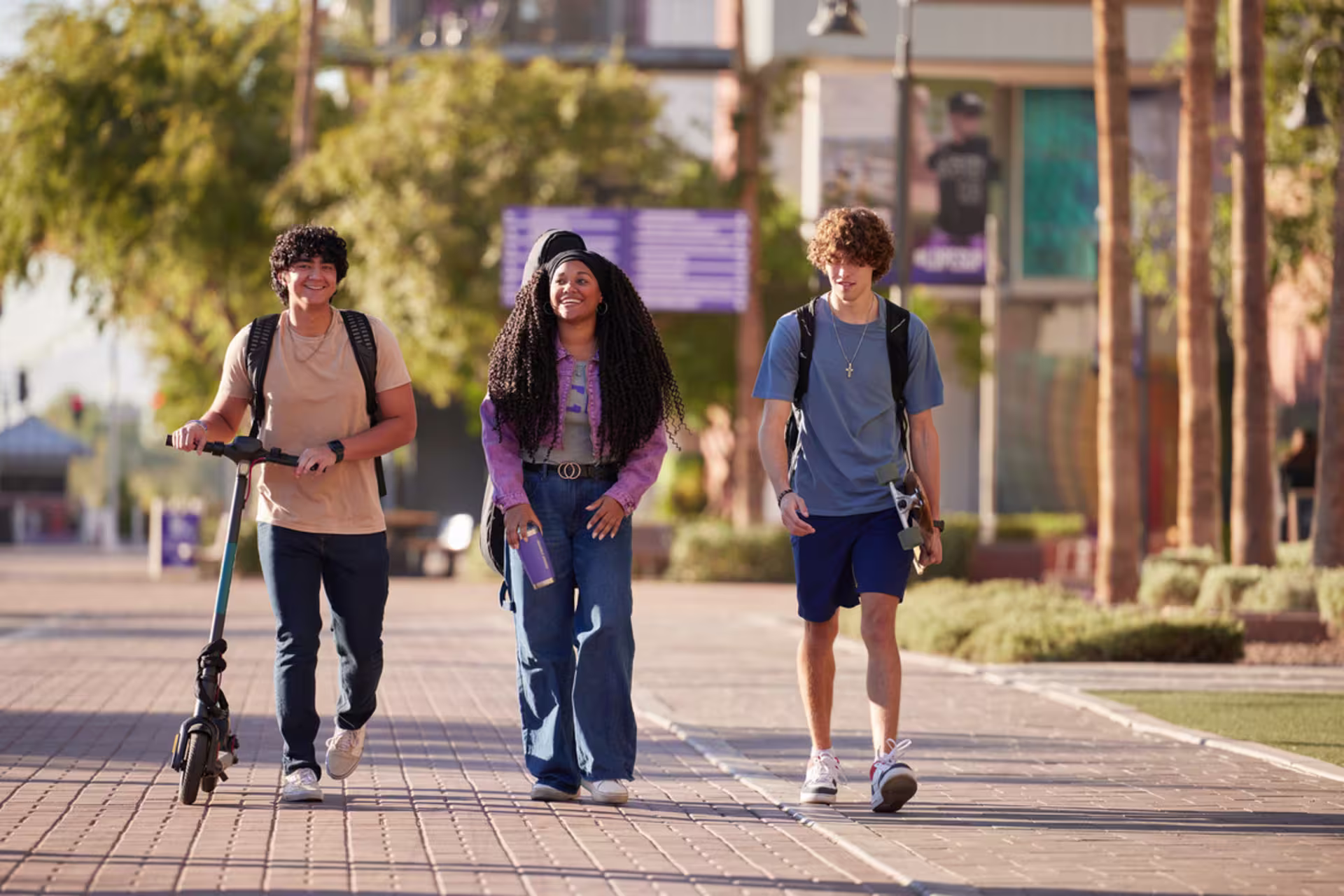 three students walk down thunder way from gcu's main entrance