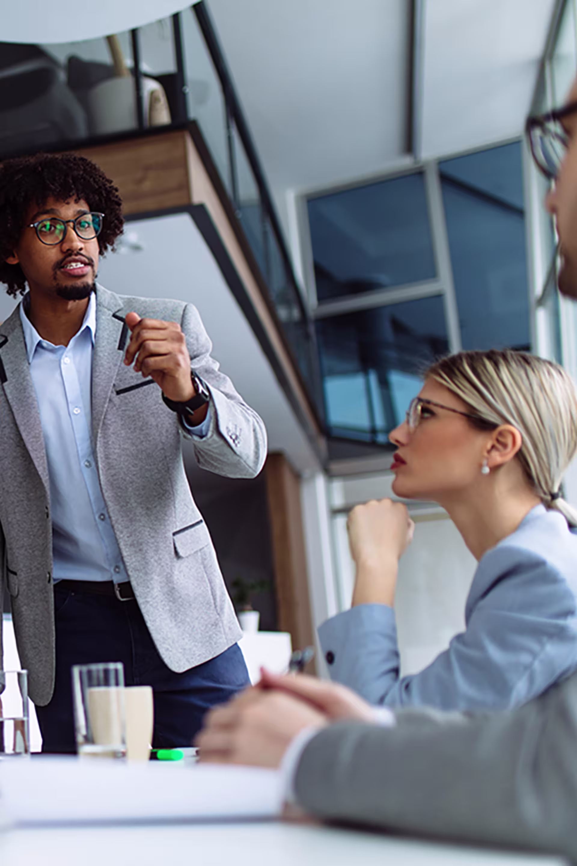 black man in a suit with tight curl fro challenges a new point of view in a business meeting while standing