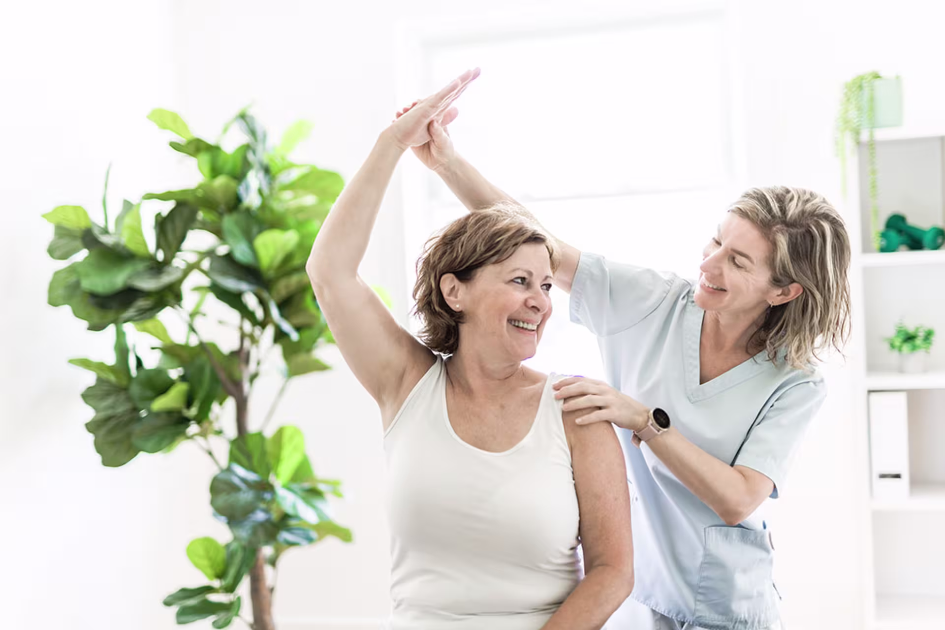 Female physiologist working with older female patient in clinic