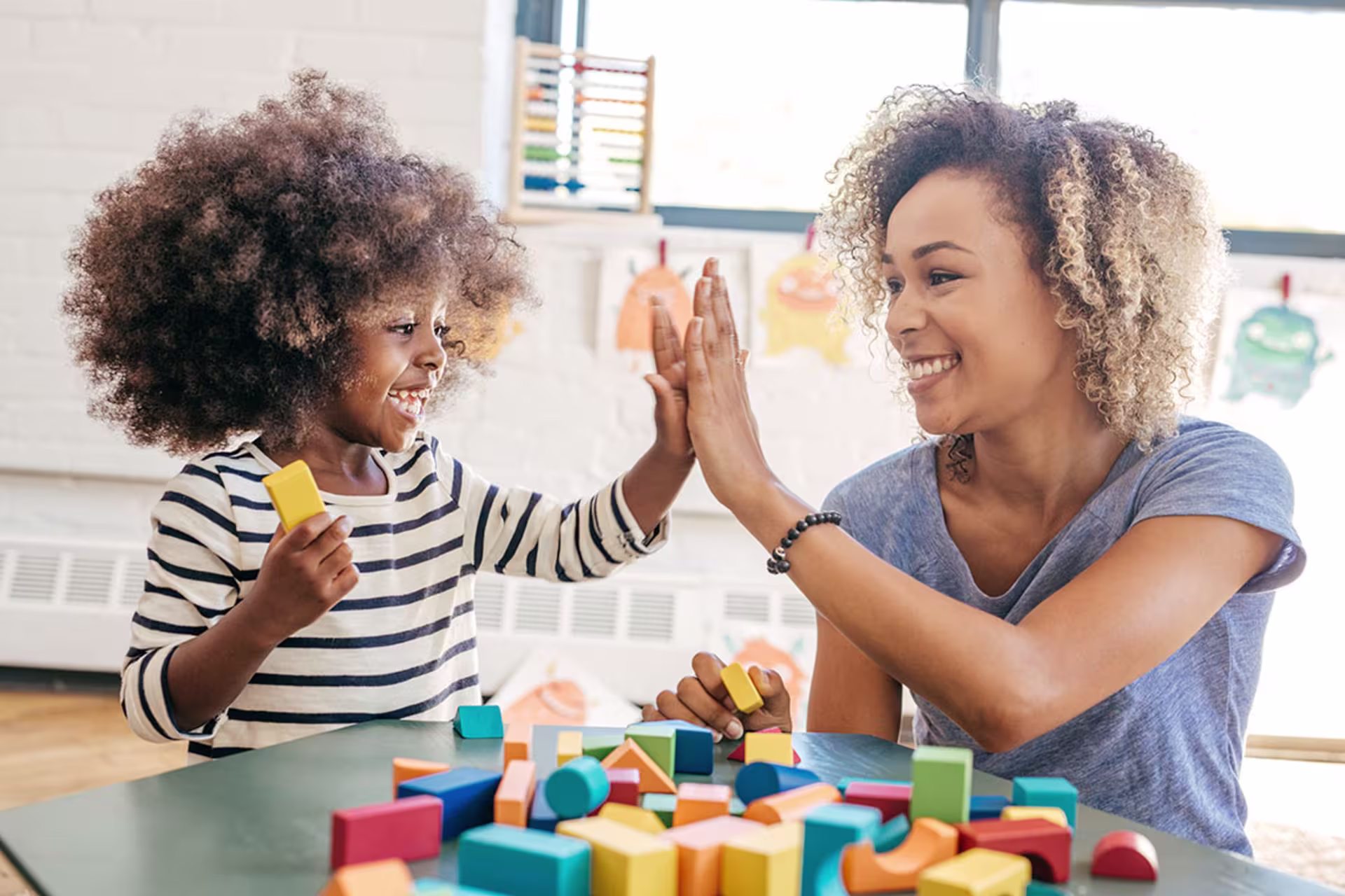Female speech therapist smiling and high-fiving with young female client