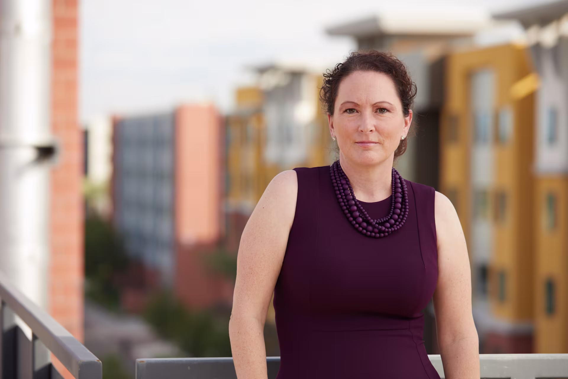 Headshot of Dr. Jennifer Lech wearing purple dress outside on college campus