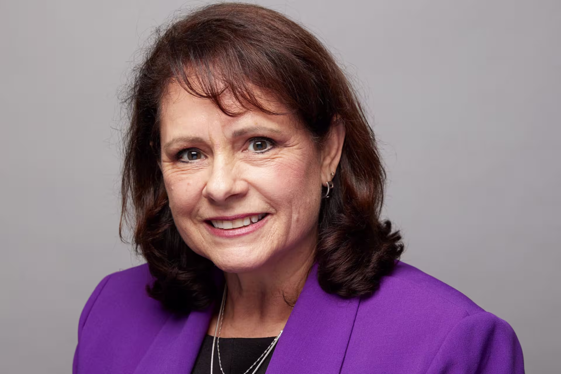 Headshot of Peggy Chase wearing purple blazer over black shirt