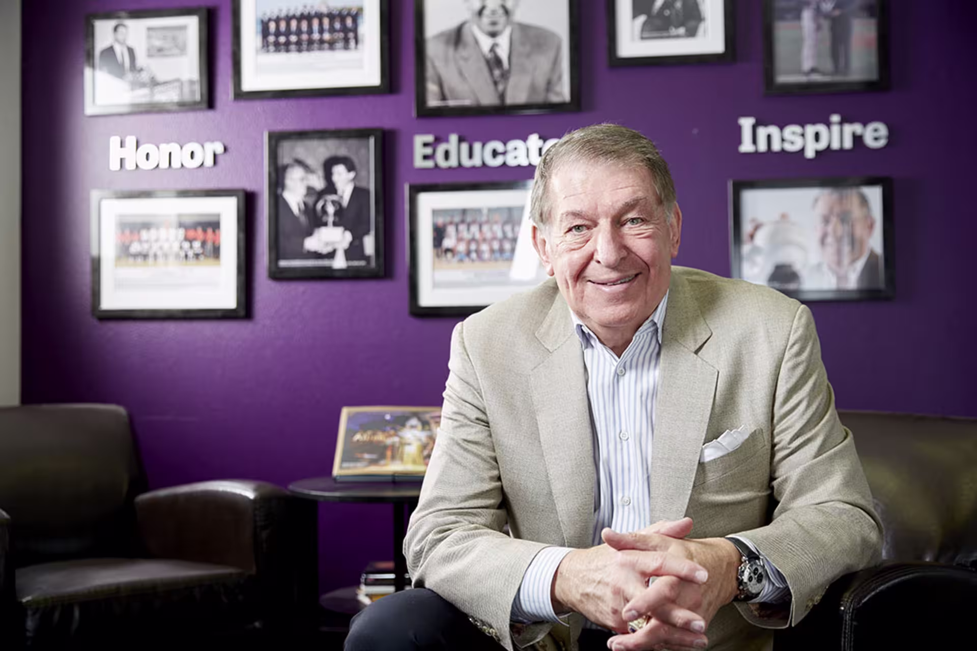 Jerry Colangelo in his office with hands intertwined and smiling at camera