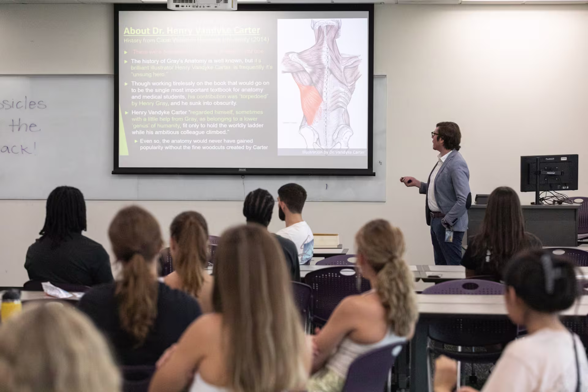 Male biology instructor giving presentation to classroom of college students