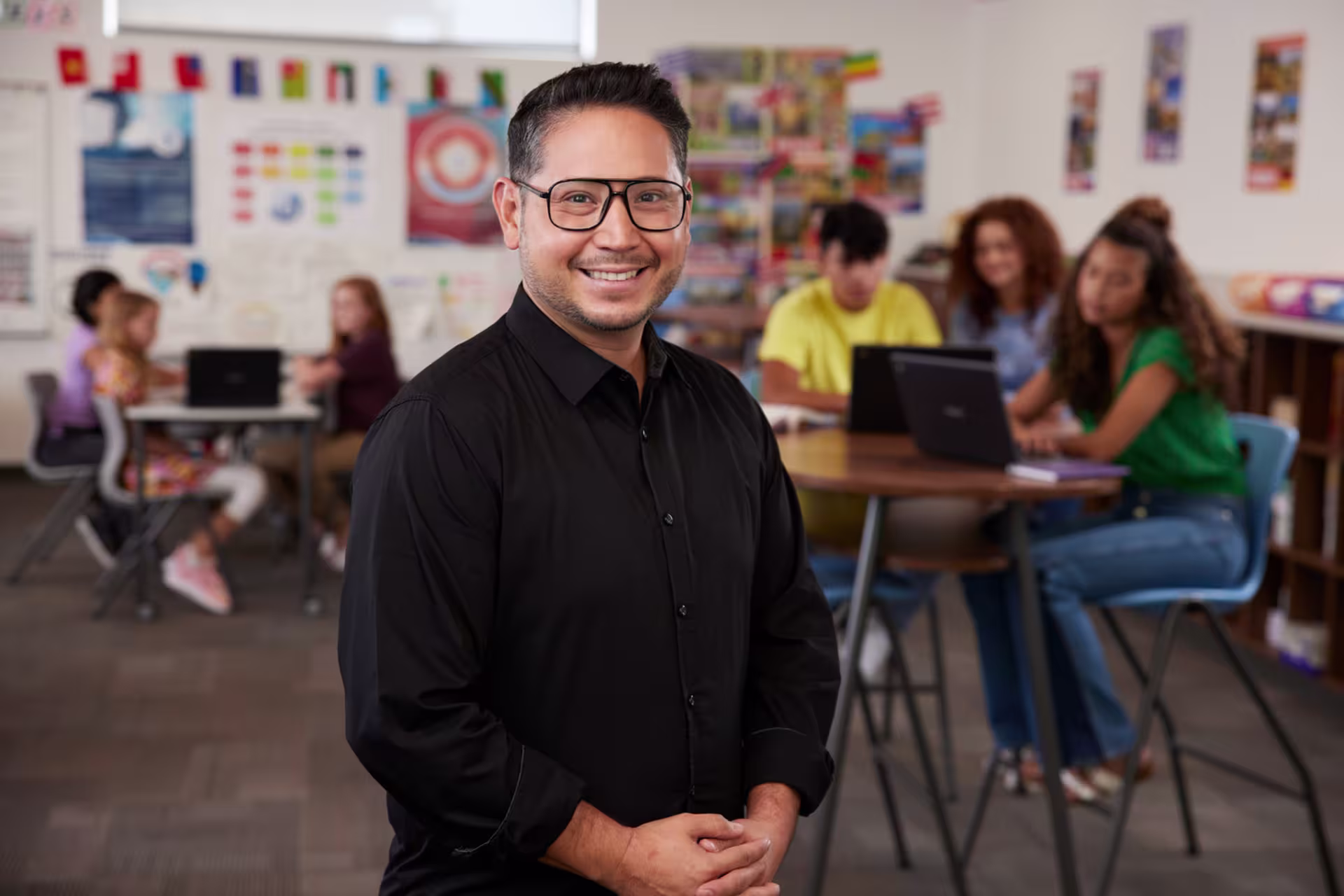 A male secondary teacher stands in front of classroom