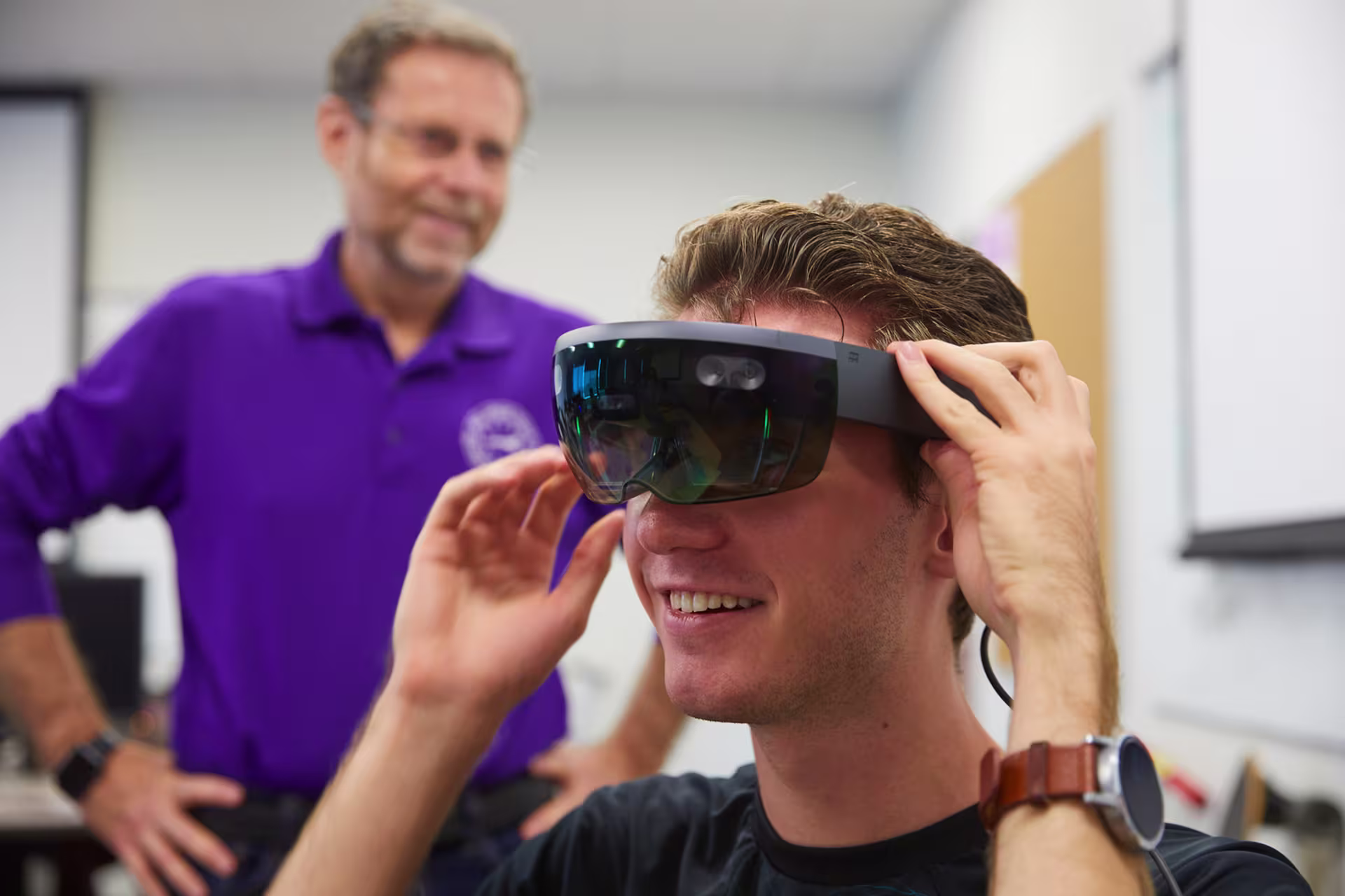 Male technology master’s instructor helping male student use VR glasses