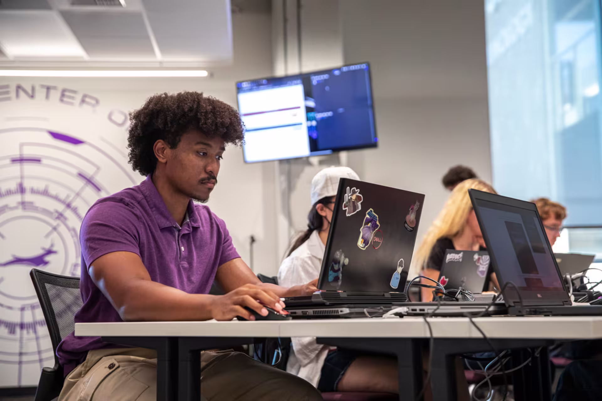 Full-Stack software development student in purple shirt working on a laptop