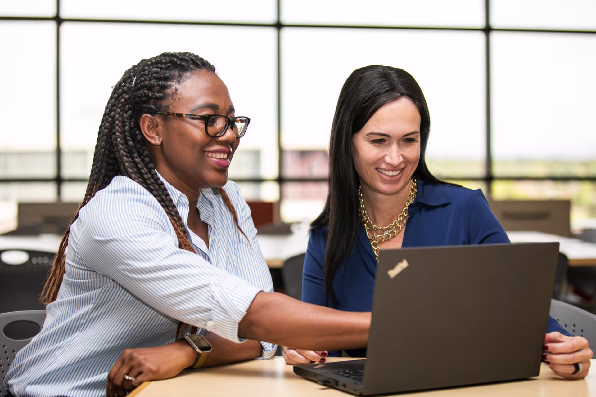 Two women working on laptop to complete language degree coursework