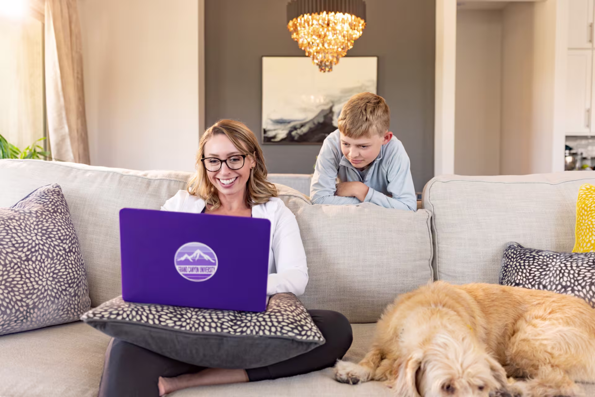 Woman sitting on couch with son and dog while earning college degree online