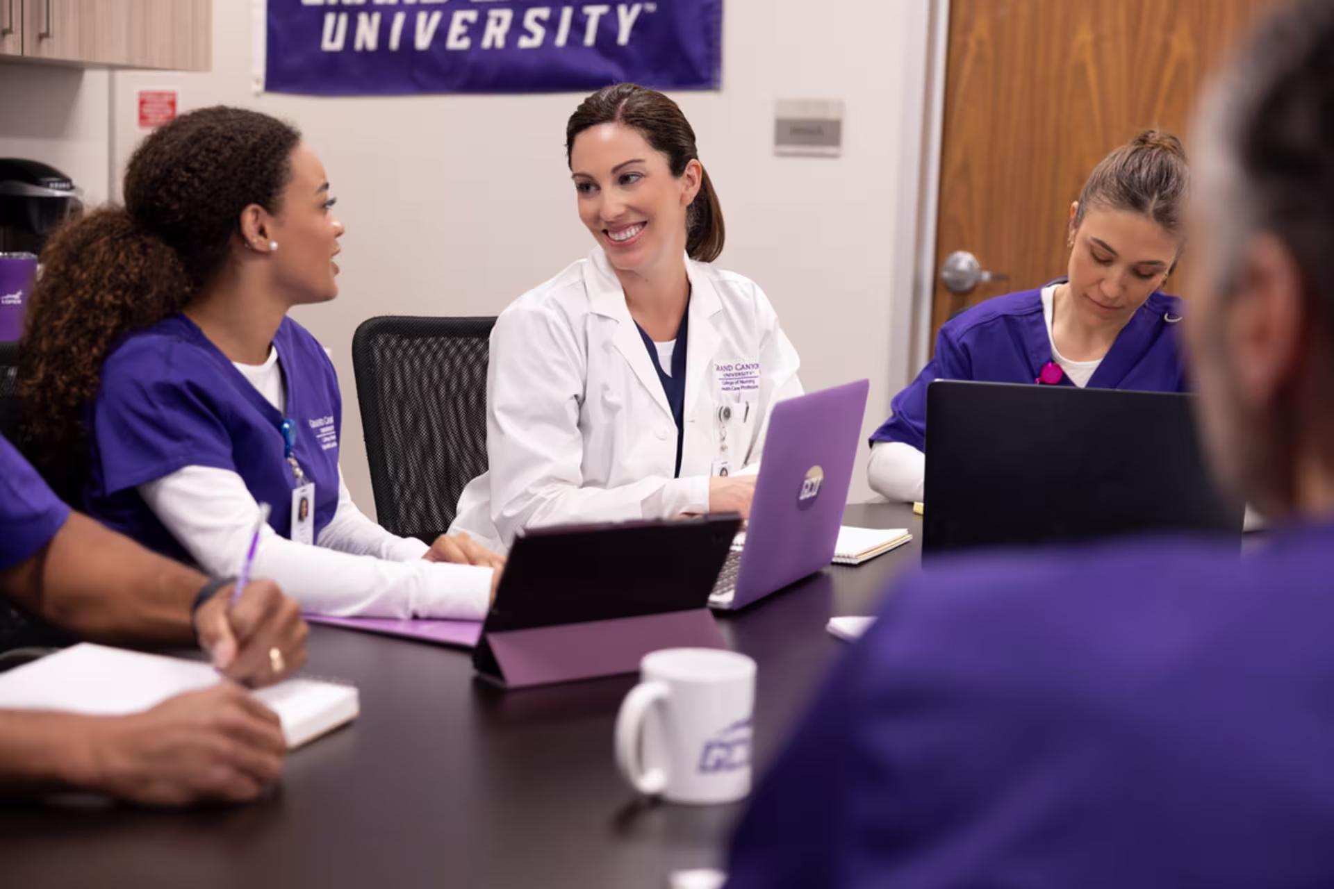 Hospital manager speaking with healthcare students at table.