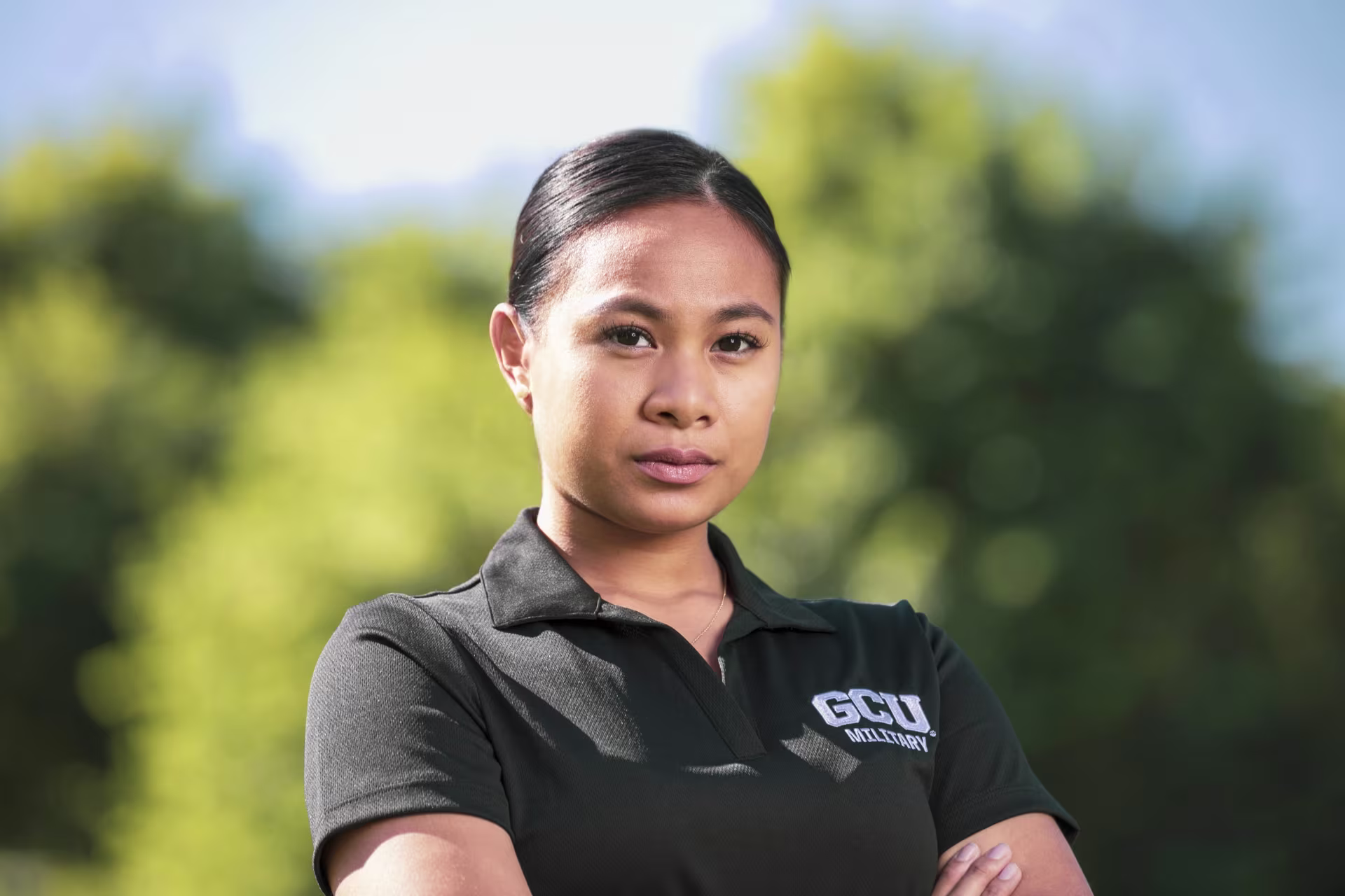 Student standing arms crossed outside