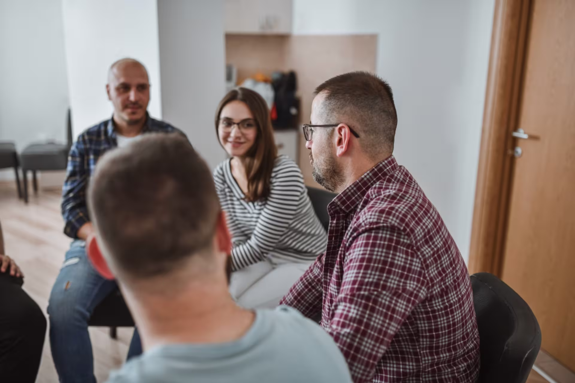 Addiction counseling group sitting together in a circle while in open discussion.