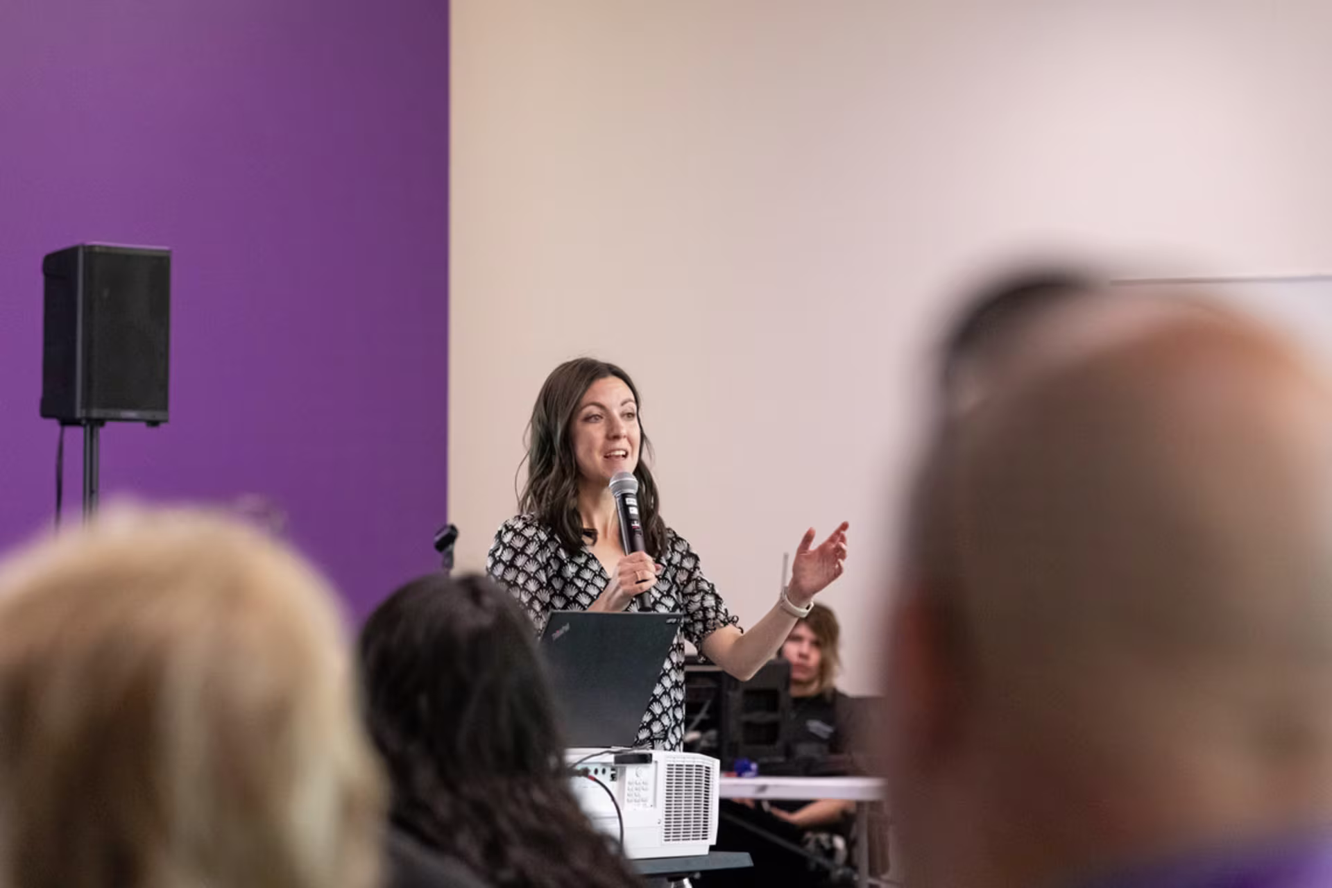 Female MDiv student speaking into microphone during class presentation.