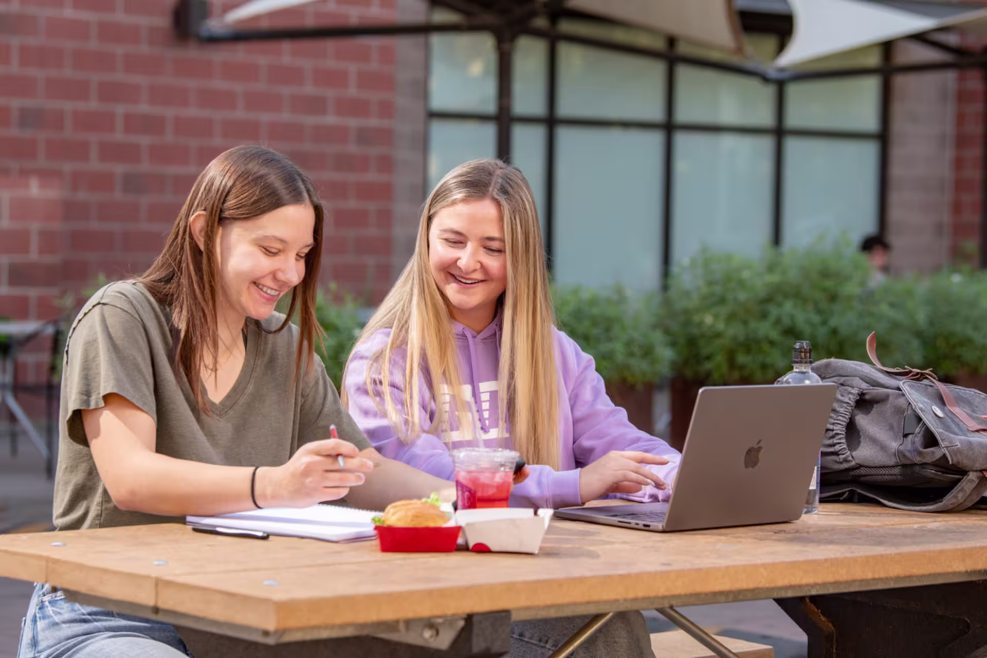 Digital film production students editing on laptop outside.