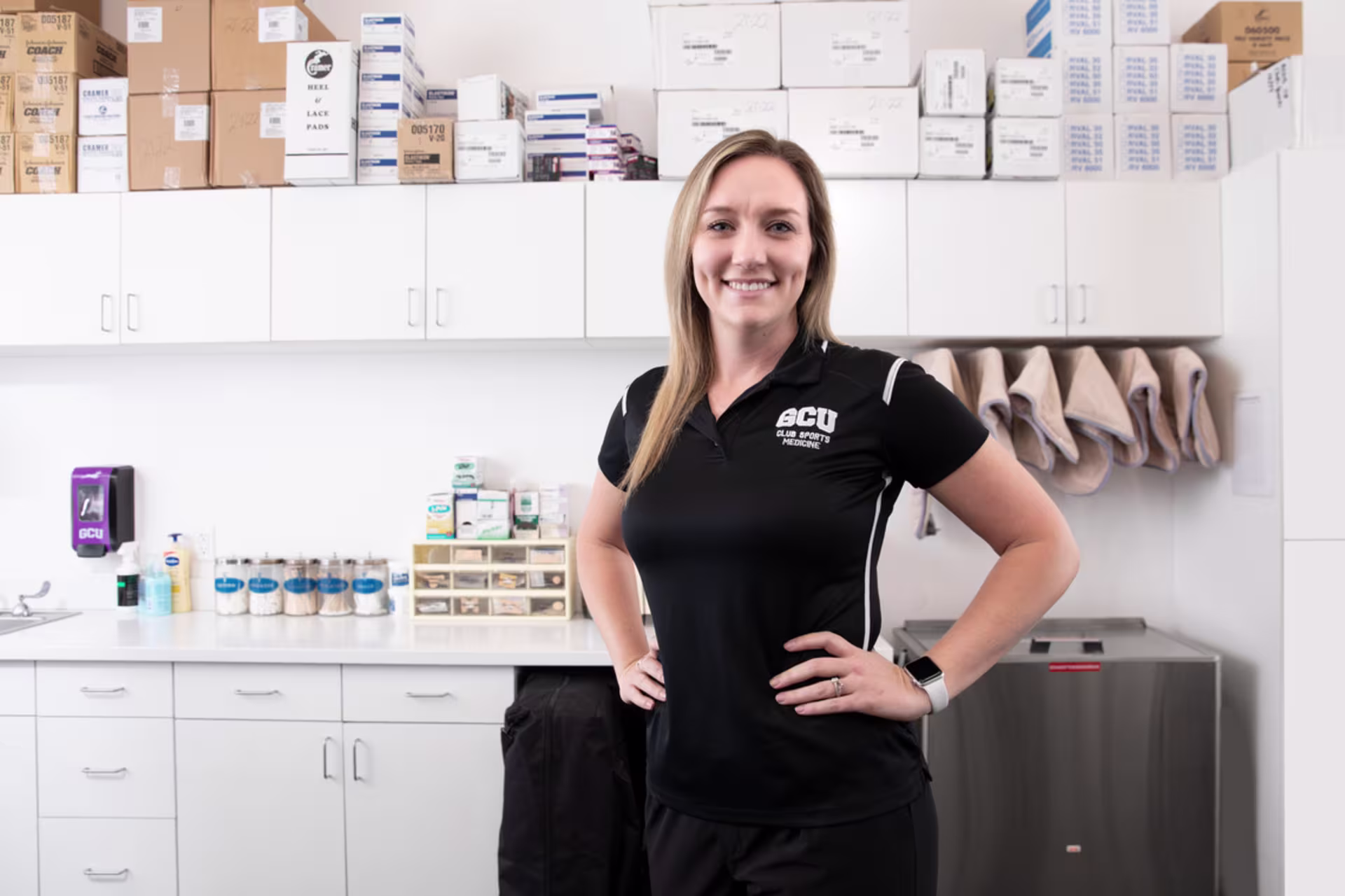 Female exercise science degree student smiling in an athletic training facility.