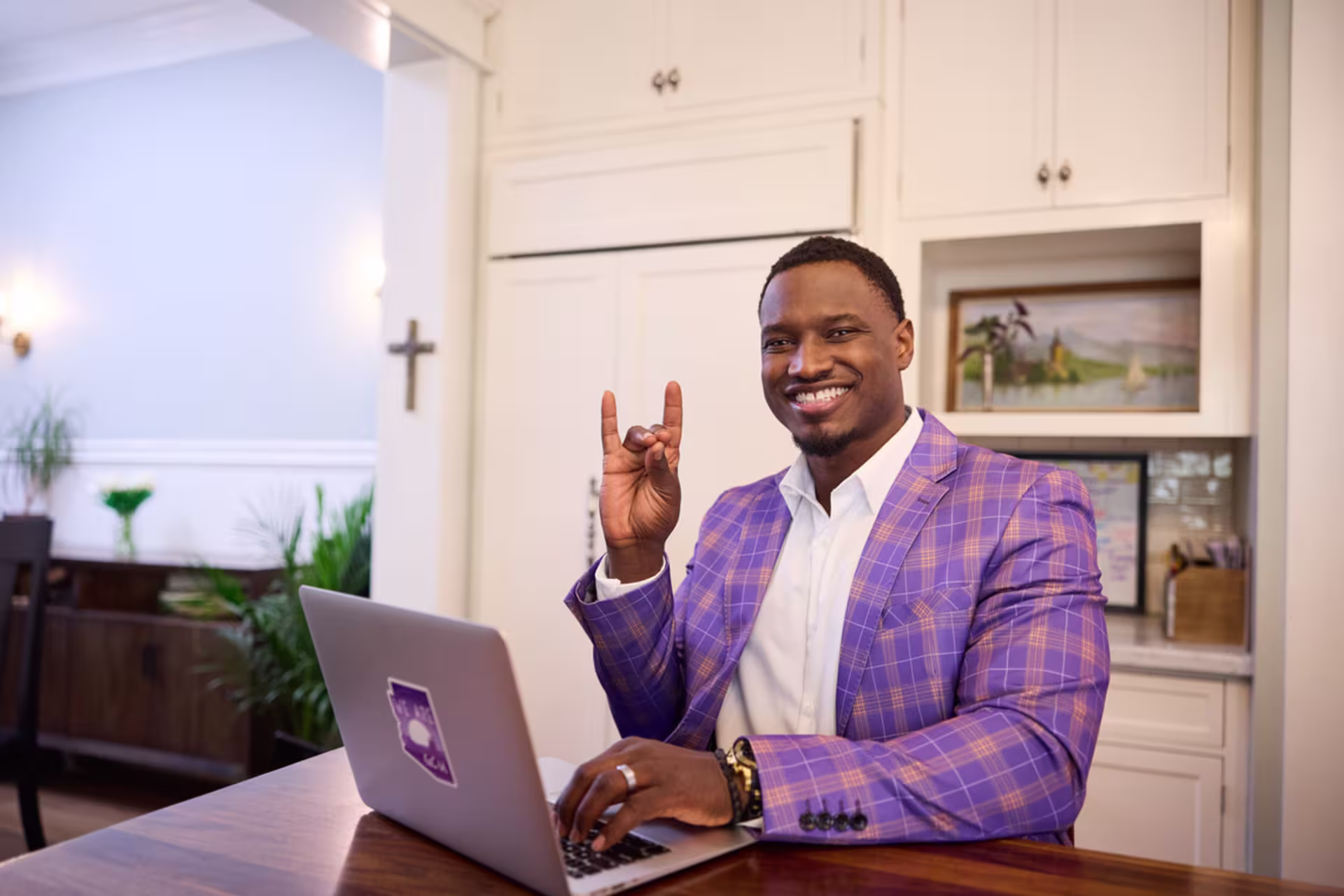 Business analytics student working on a laptop at home in a purple plaid blazer.