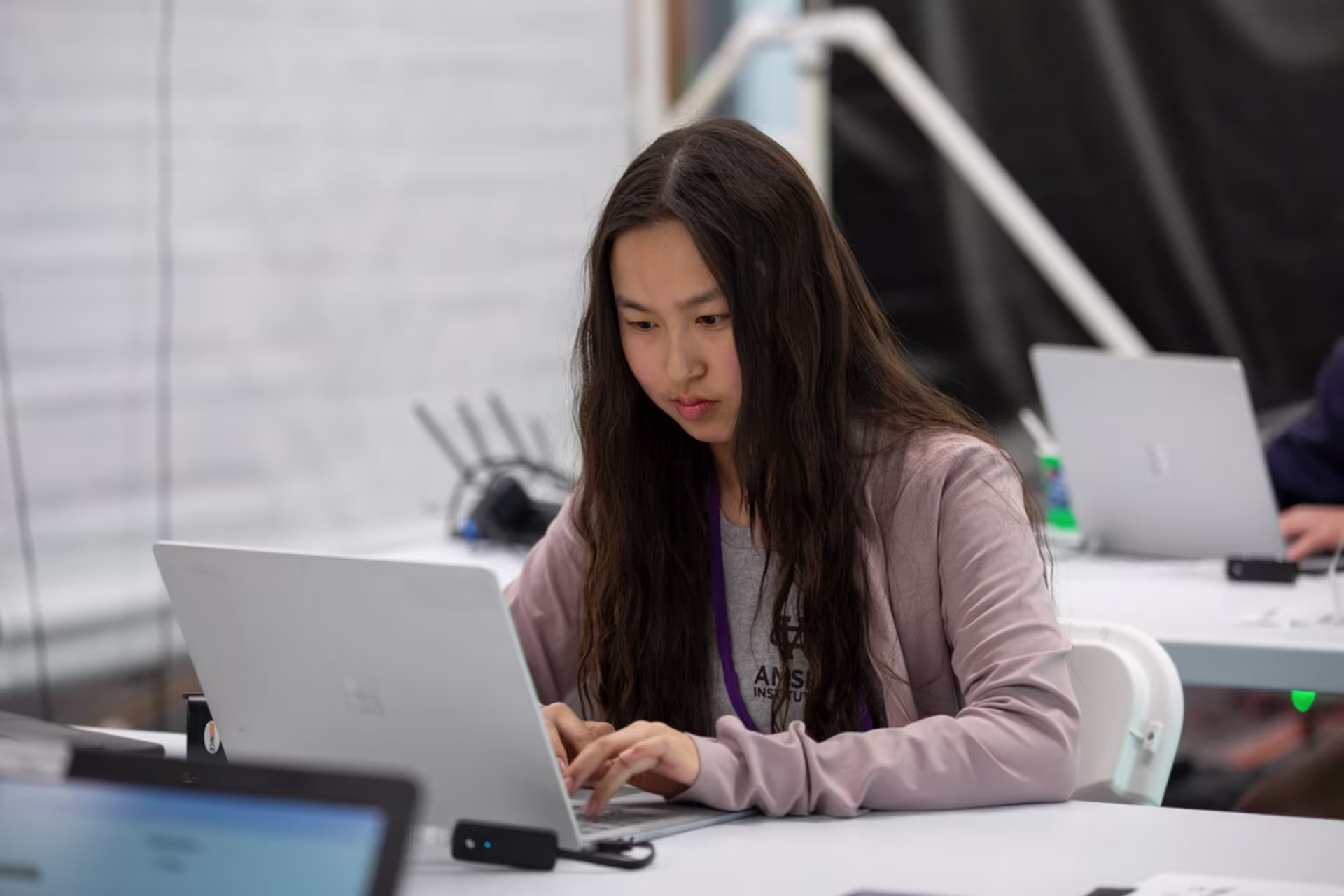 Online artificial intelligence student working in a lab setting on a laptop.
