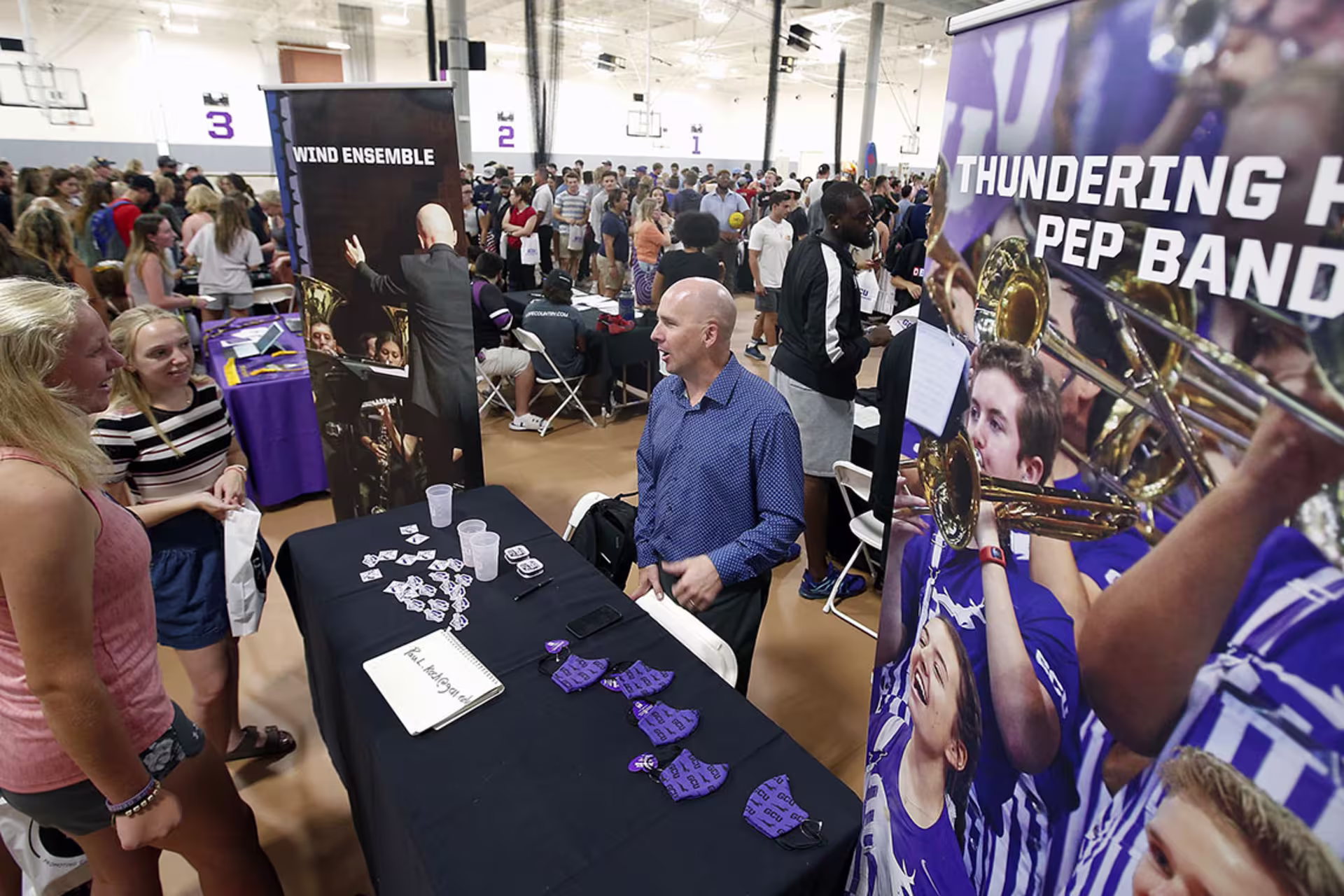 Male Thundering Herd Pep Band member speaking with potential female members at club fair.
