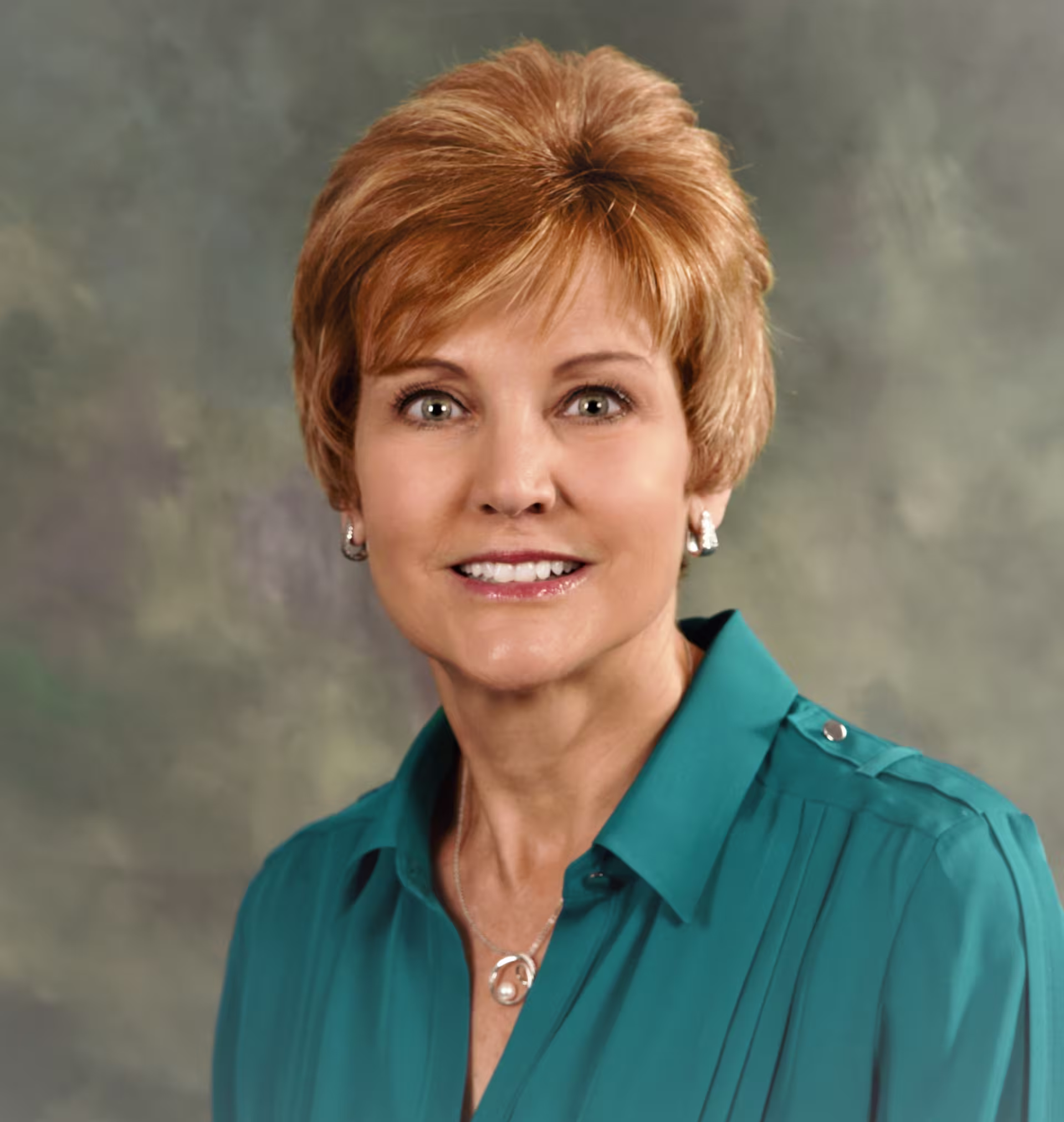 A women wearing a teal button down shirt looking at camera. 