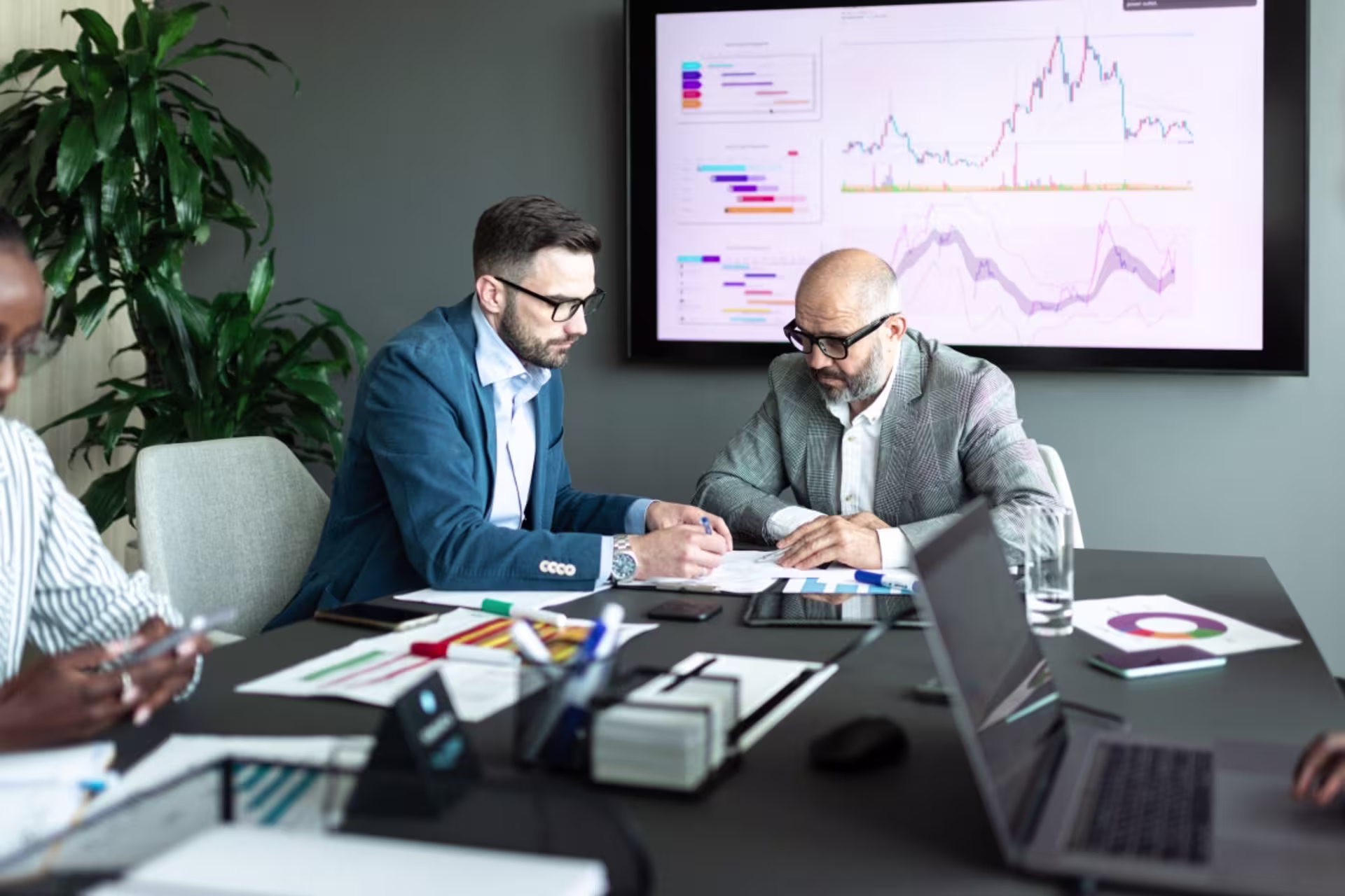 Male data scientists work together in a conference room, reviewing data and graphs.