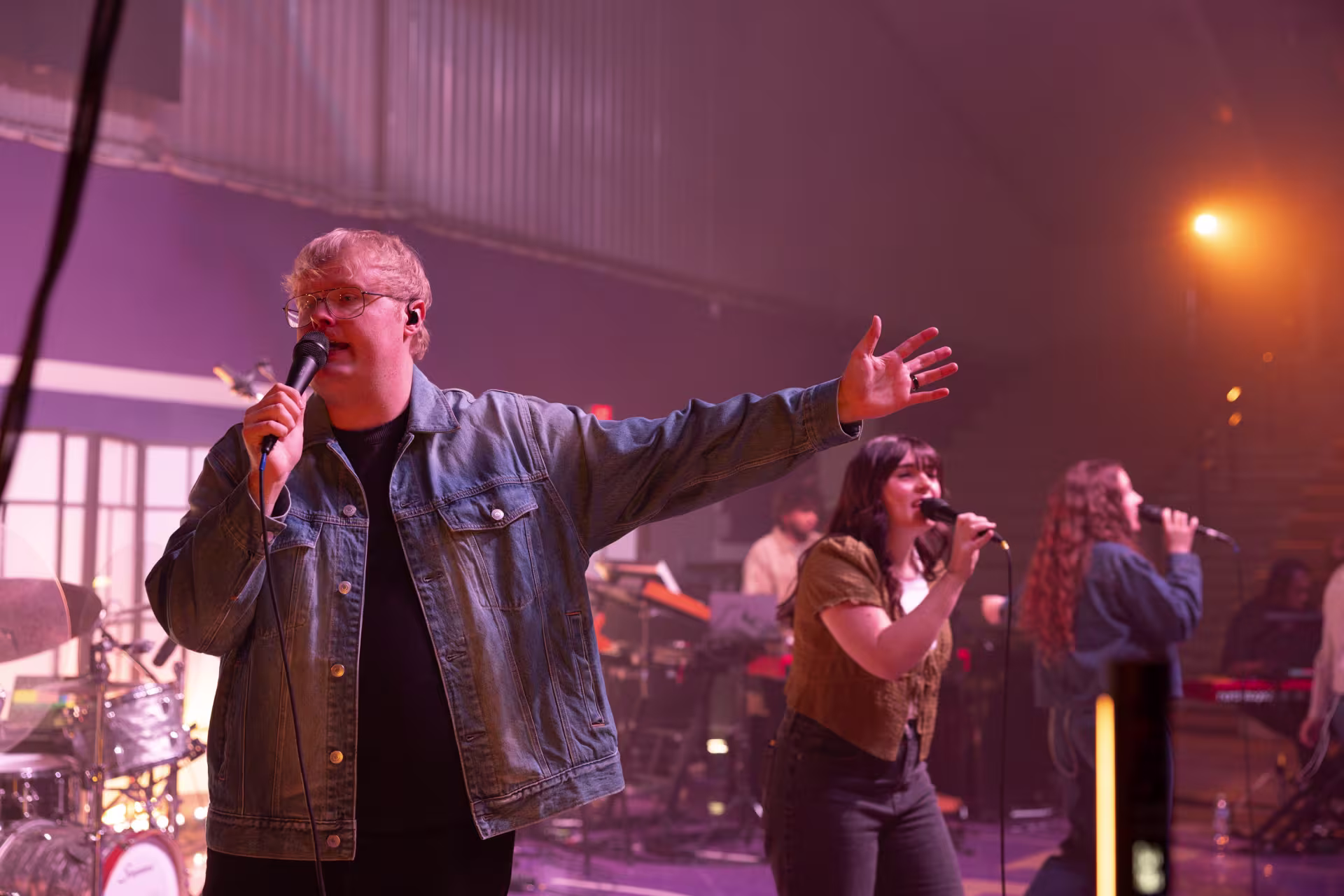 Worship band leading music on stage with vocalists and musicians performing, highlighting collaborative worship ministry in a live setting.
