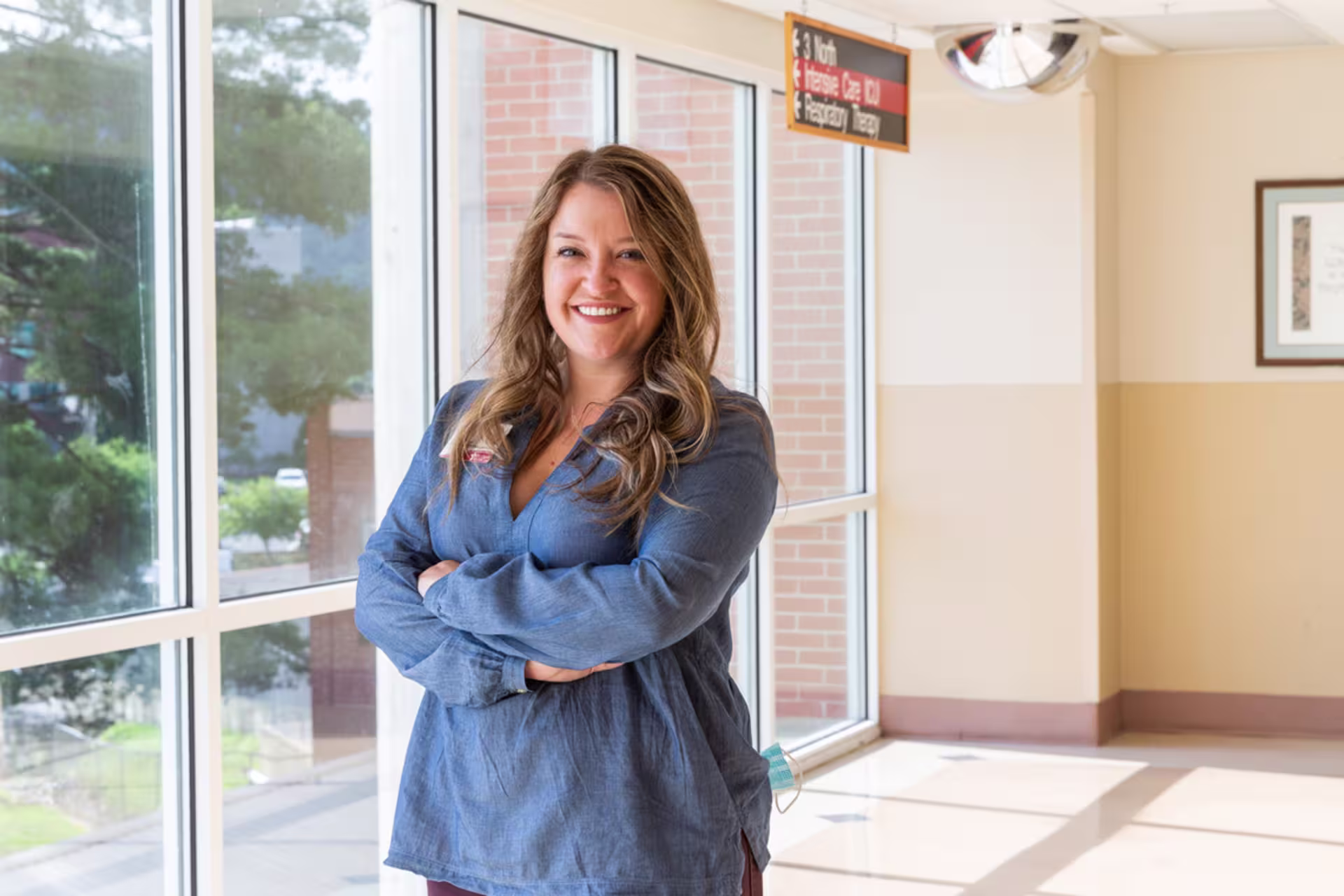 Health systems management MBA student standing in a hospital setting with her arms crossed.