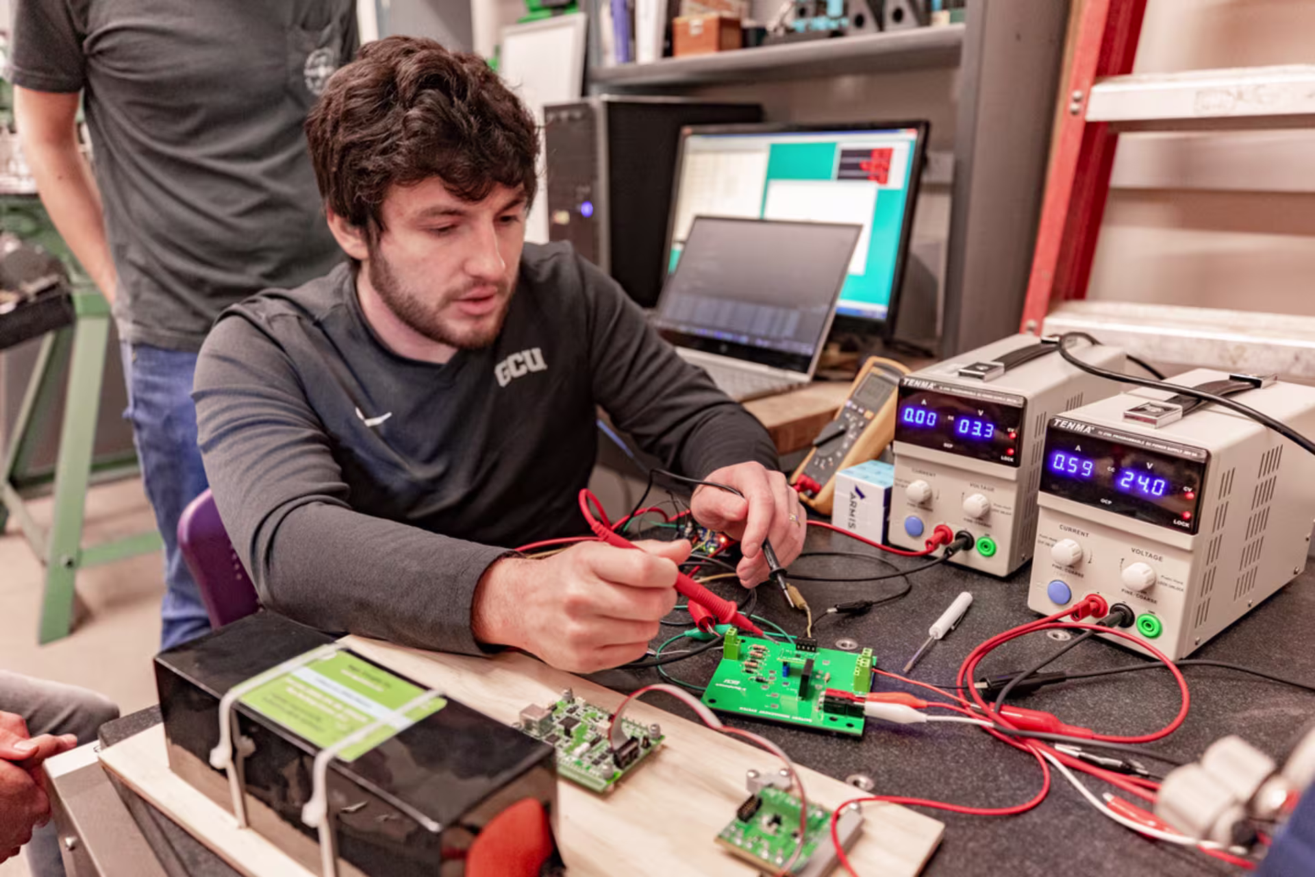 GCU engineering student working in an electronics lab, testing circuits and using diagnostic tools.