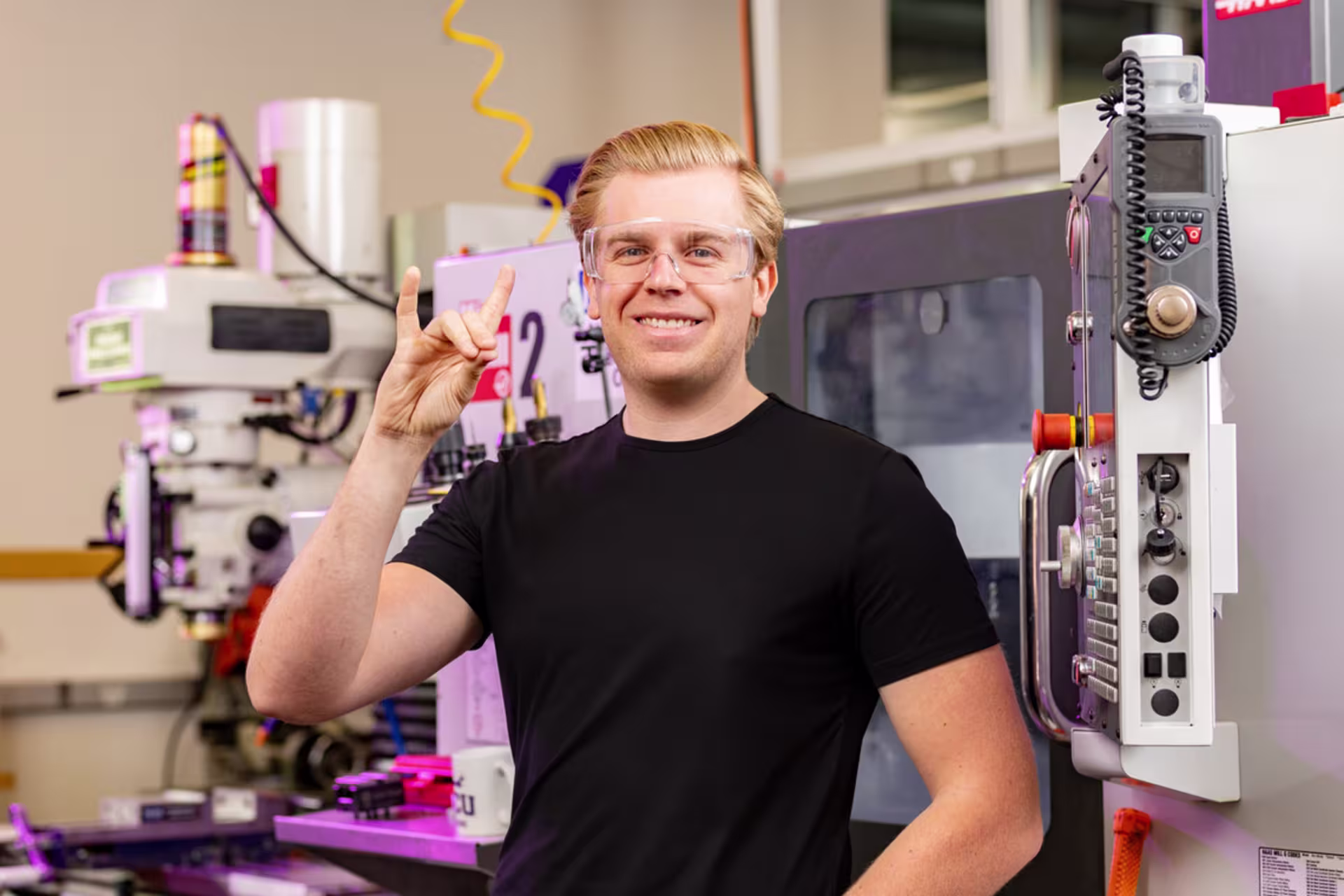 Student in a mechanical engineering technology mechatronics lab with advanced machinery. 